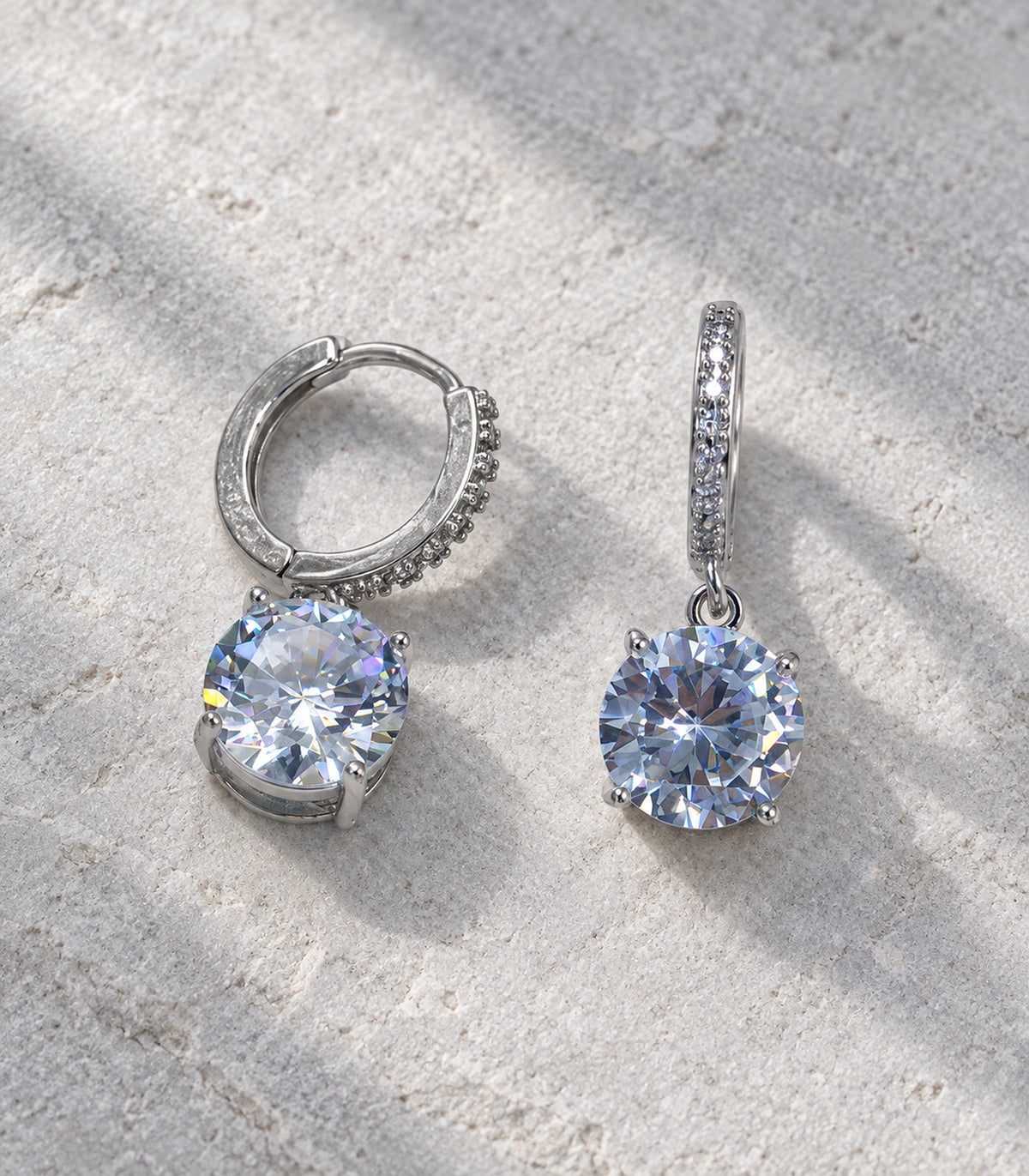 JIMIKI Silver-Tone Oversized Round Solitaire Drop Huggie Earrings in Silver / Clear, editorial flat lay