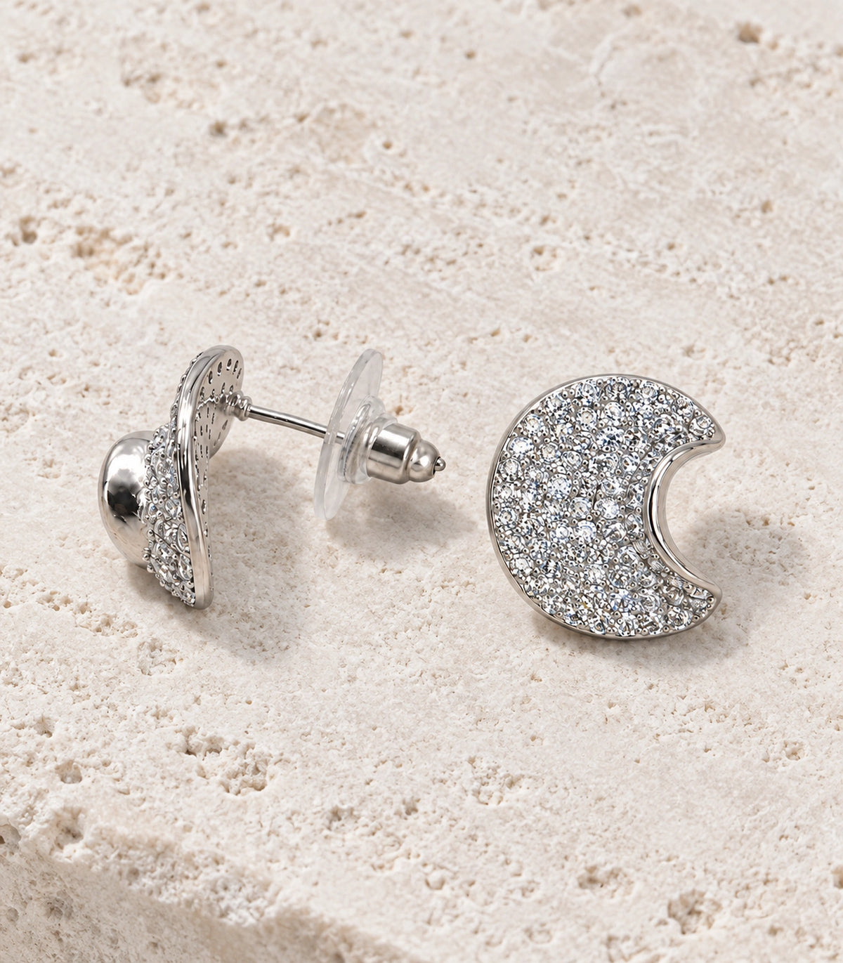 JIMIKI Pave Crescent Moon Stud Earring Pair in Silver-tone, editorial flat lay #color_silver-tone
