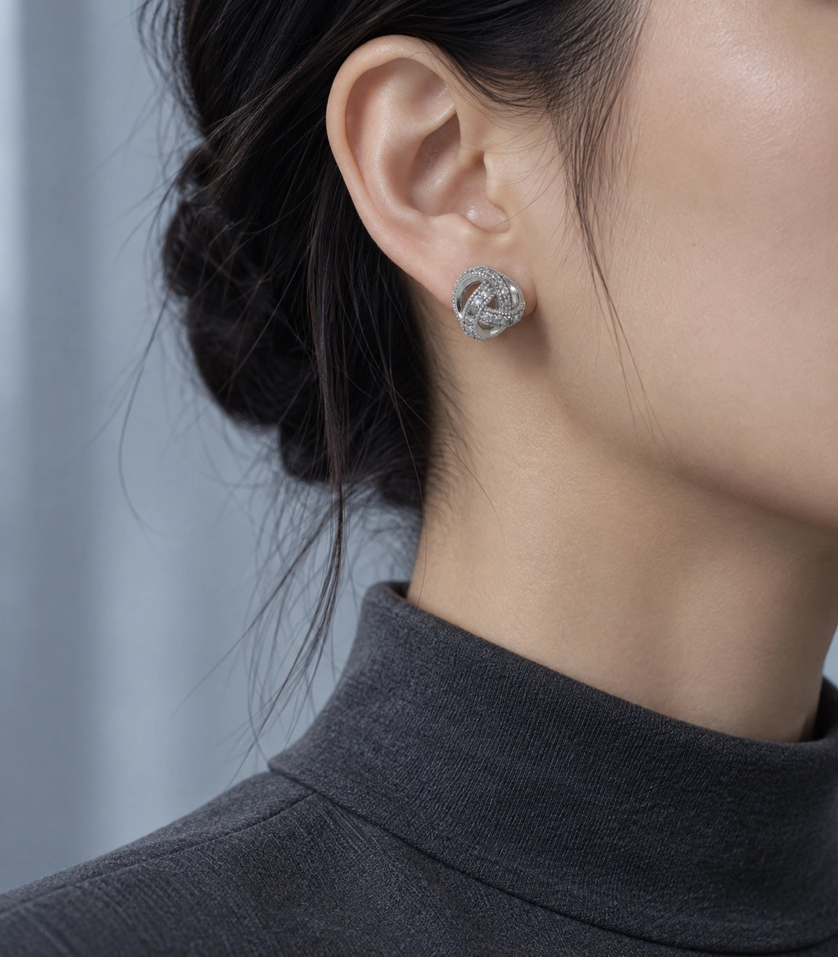 JIMIKI Silver-Tone Pavé Interwoven Knot Stud Earrings in Silver / Clear, editorial model view