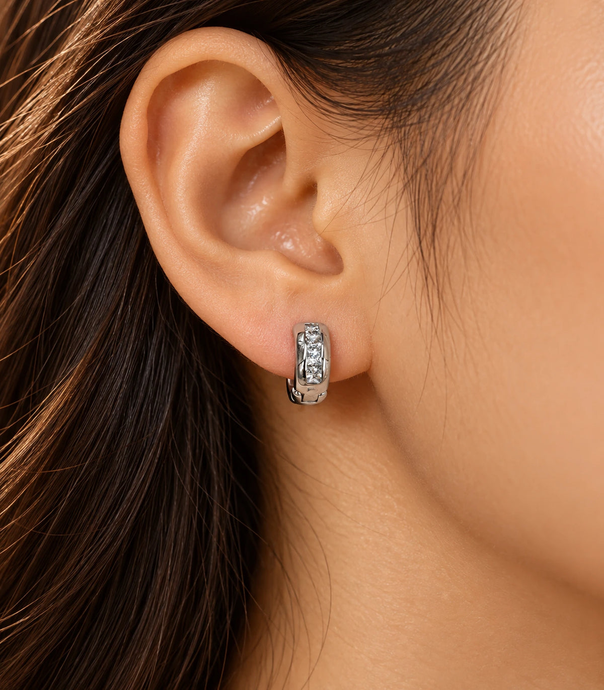 JIMIKI Silver Rectangular Crystal Channel Huggie Hoop Earrings, worn in warm editorial lighting #color_silver