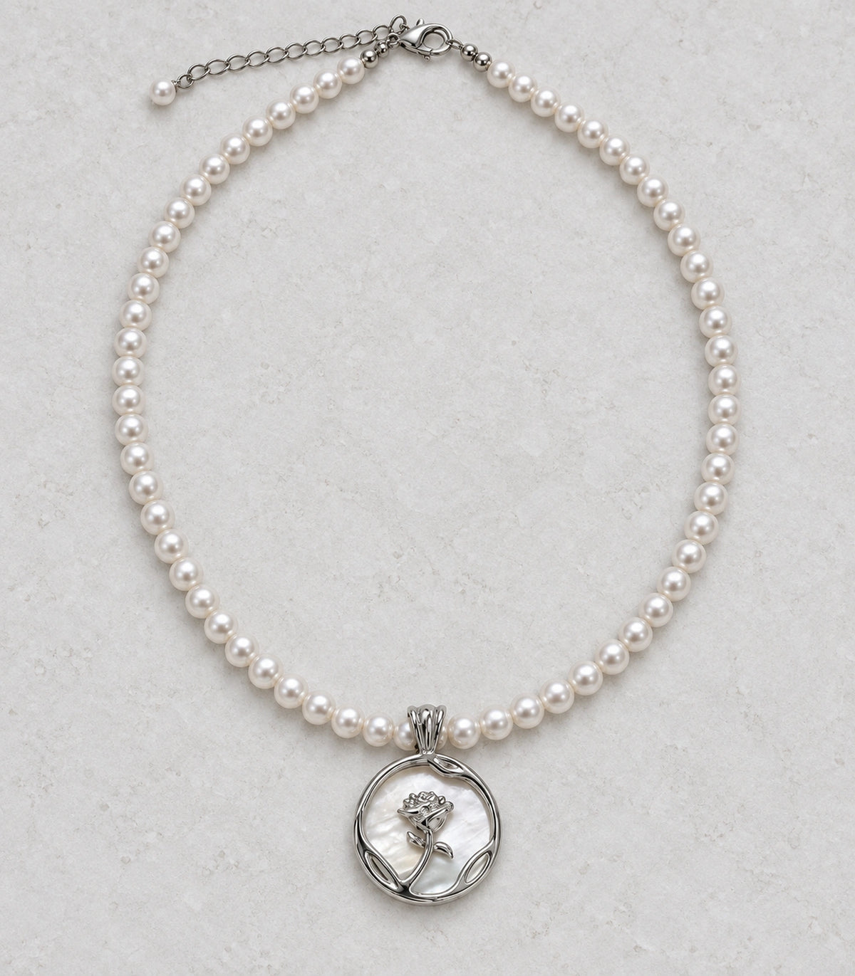 JIMIKI Silver Tone Rose Medallion Pearl Style Necklace in Silver tone / white, editorial flat lay