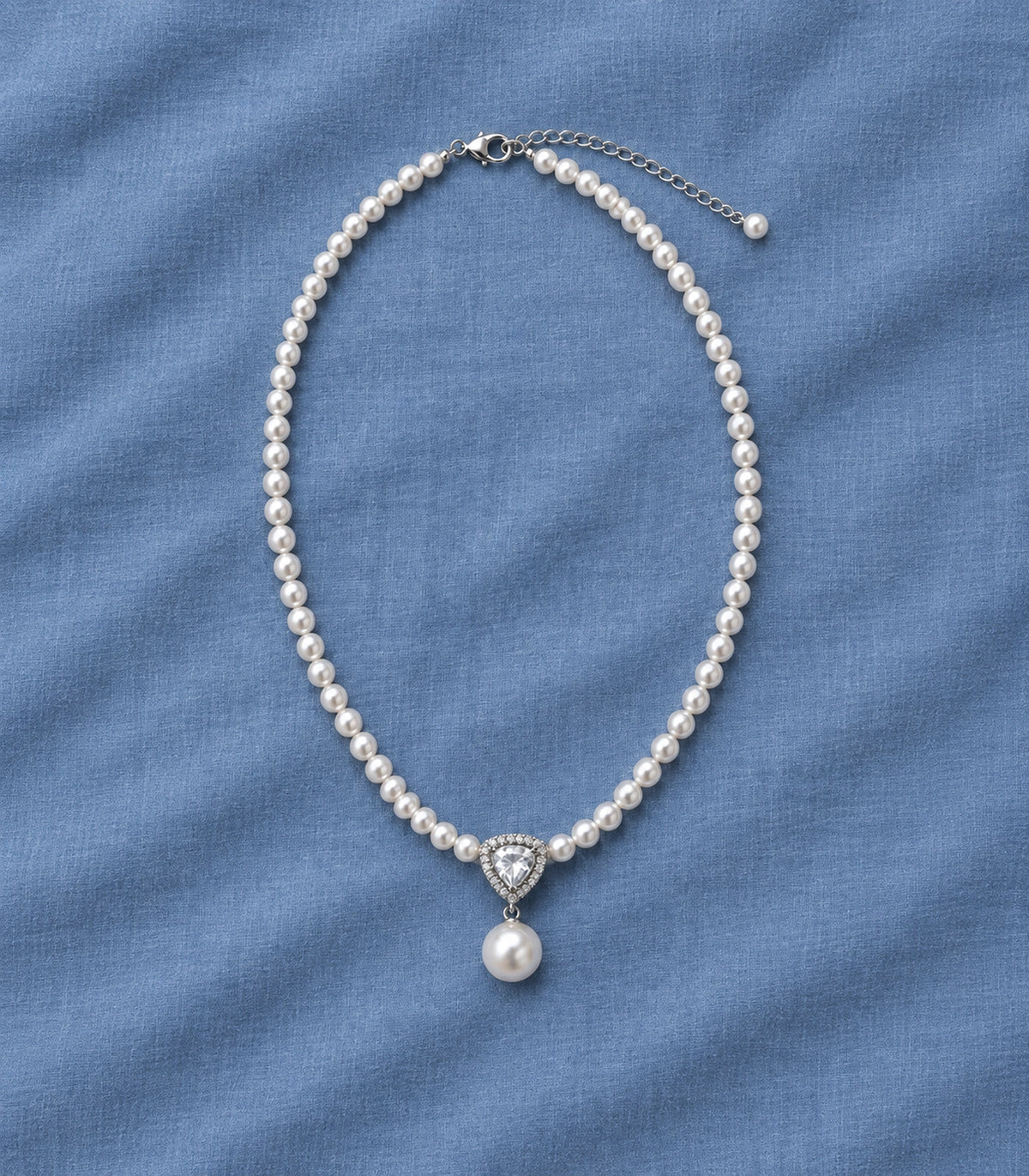 JIMIKI Silver Tone Shield Crystal Pearl Drop Necklace in Silver / White, editorial flat lay
