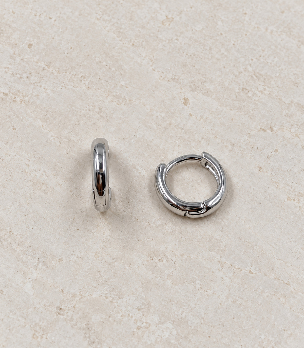 Silver Tone Smooth Huggie Hoop Earrings — complete matching pair flat lay