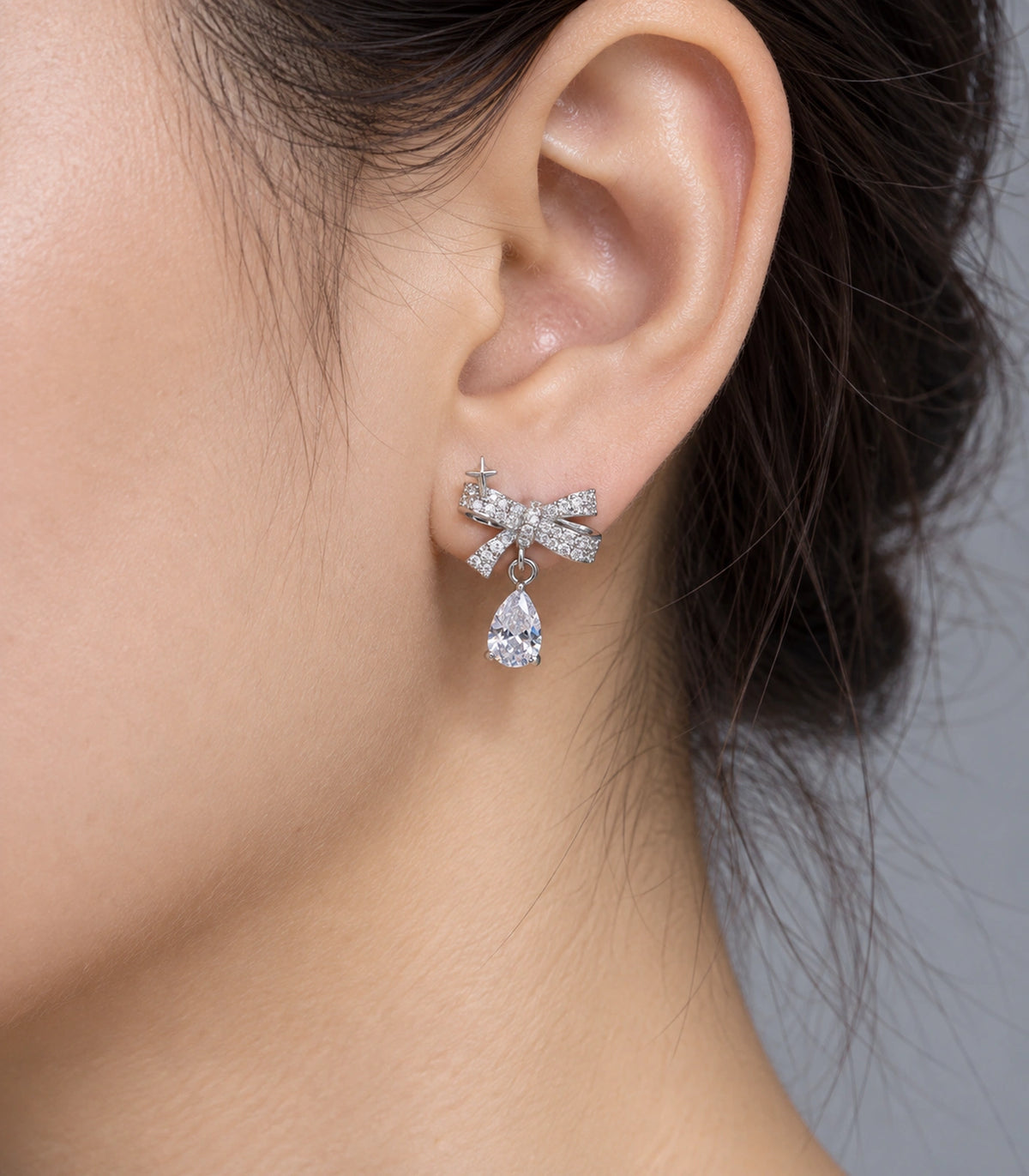 JIMIKI Silver-Tone Star Bow Pear-Drop Earrings in Silver / Clear, close-up detail