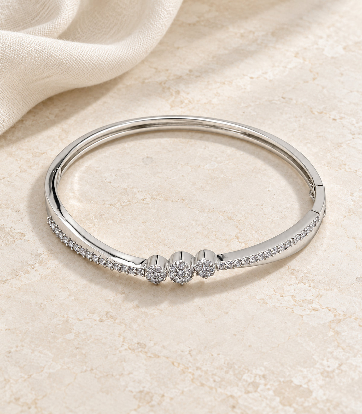 Complete silver-tone three-flower crystal hinged bangle on pale stone and ivory linen