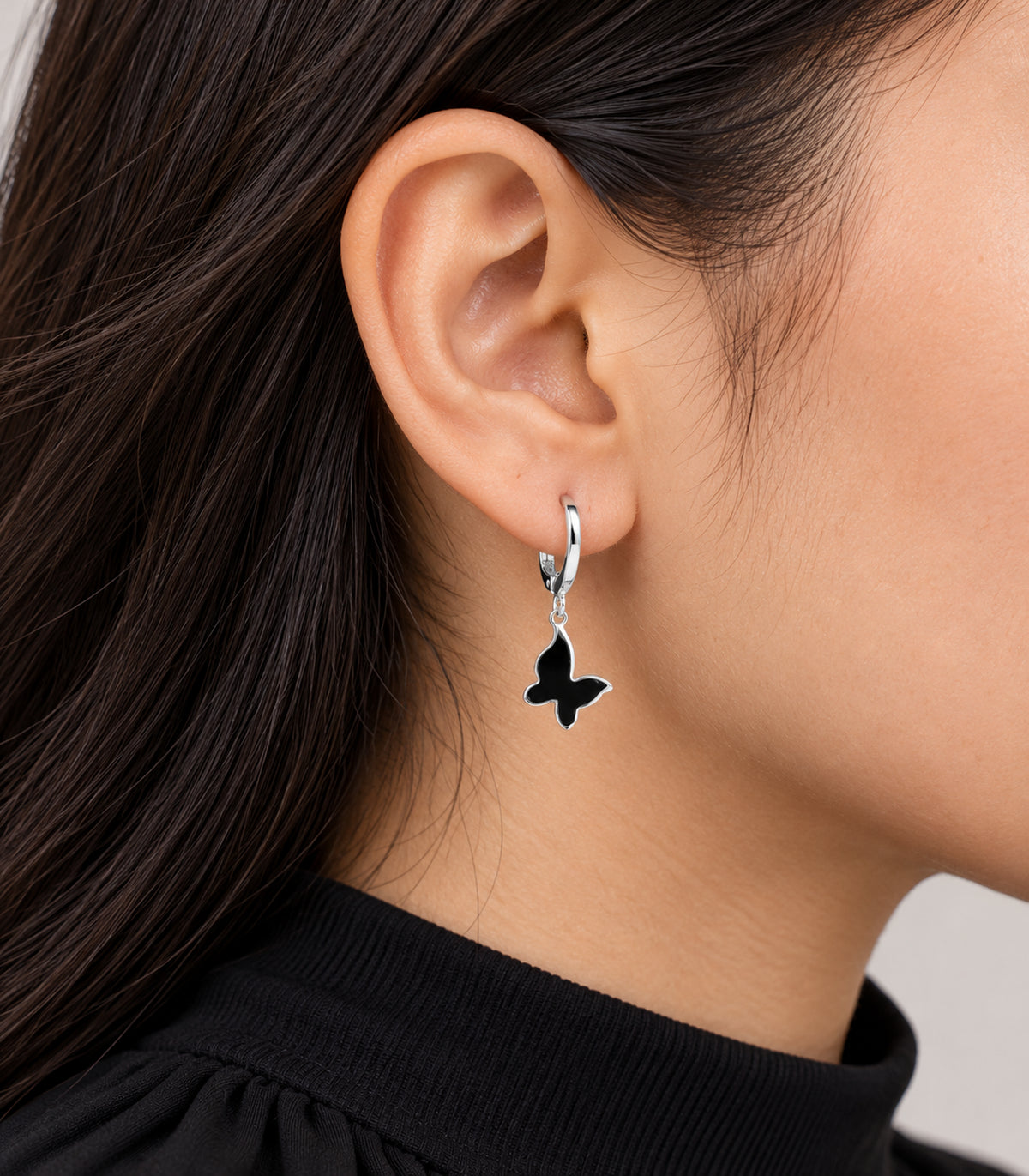 Editorial worn view of earrings from the silver-tone butterfly hoop set