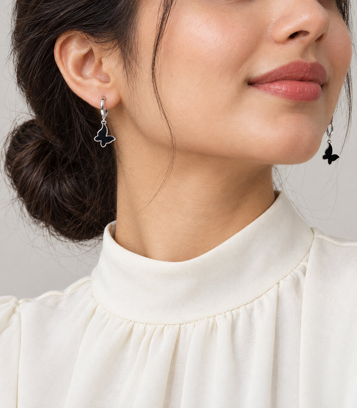 Worn view of earrings from the silver-tone three-pair butterfly hoop set