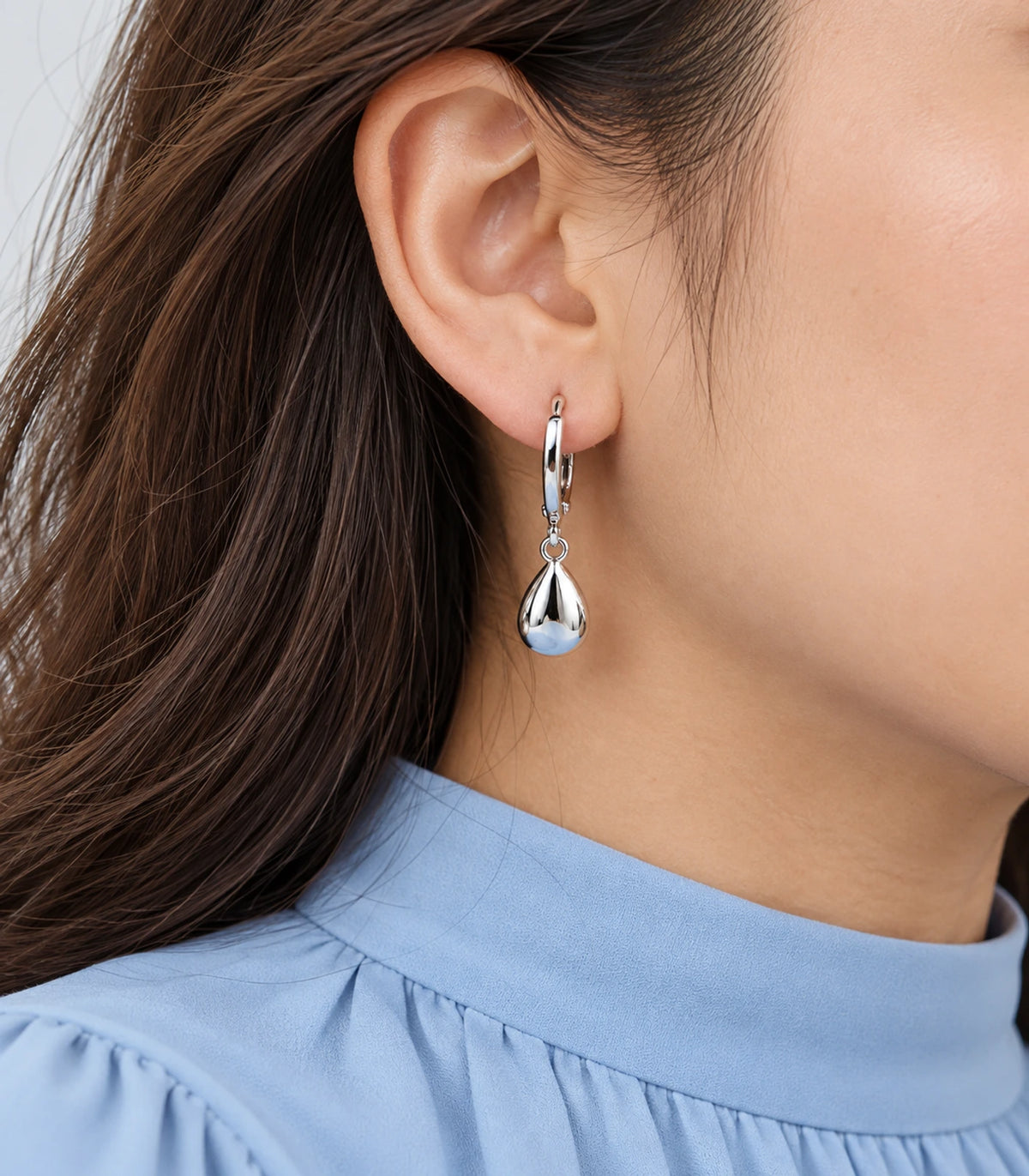 Silver-tone puffed teardrop hoop earring shown in closeup
