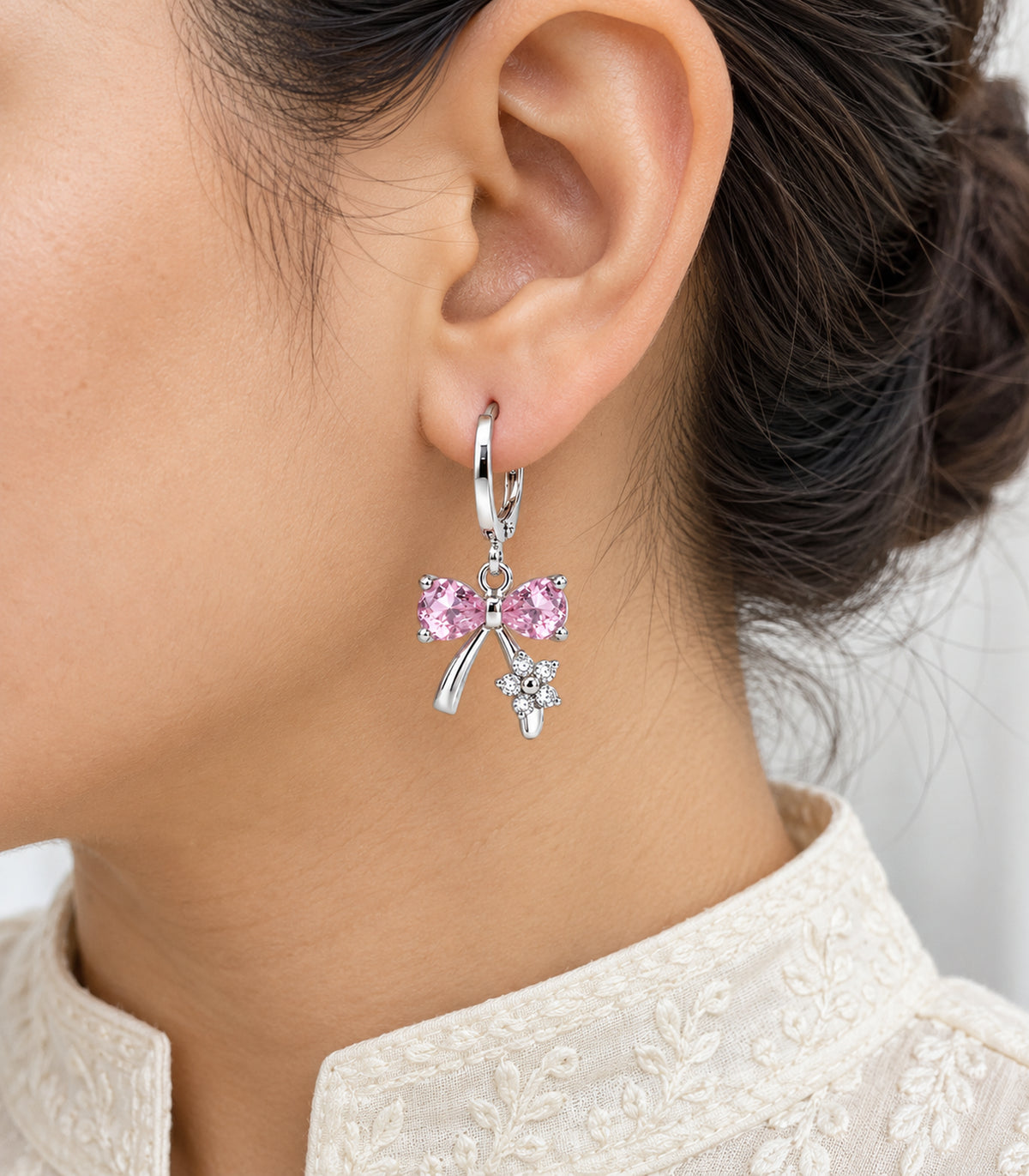 Worn closeup of one pink crystal bow hoop, ribbon tails and clear flower detail from the set
