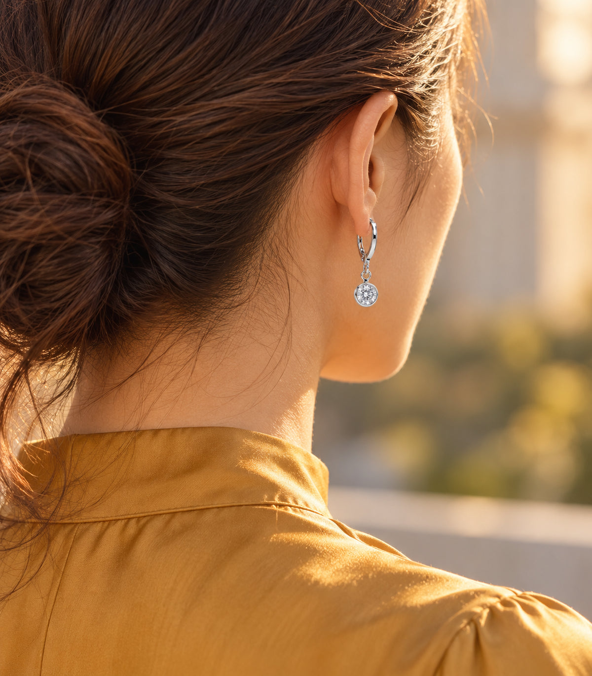 One round clear bezel crystal hoop from the silver-tone three-pair set, worn with an ochre collar.