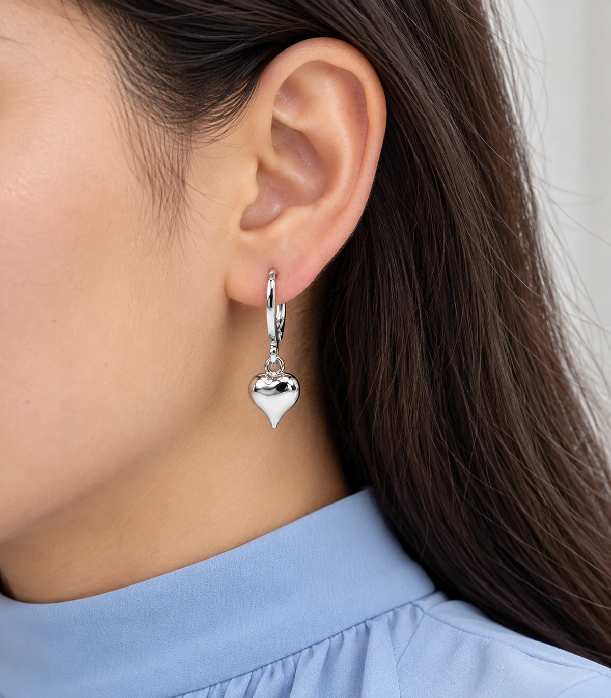 Close view of a silver-tone smooth heart charm hoop earring