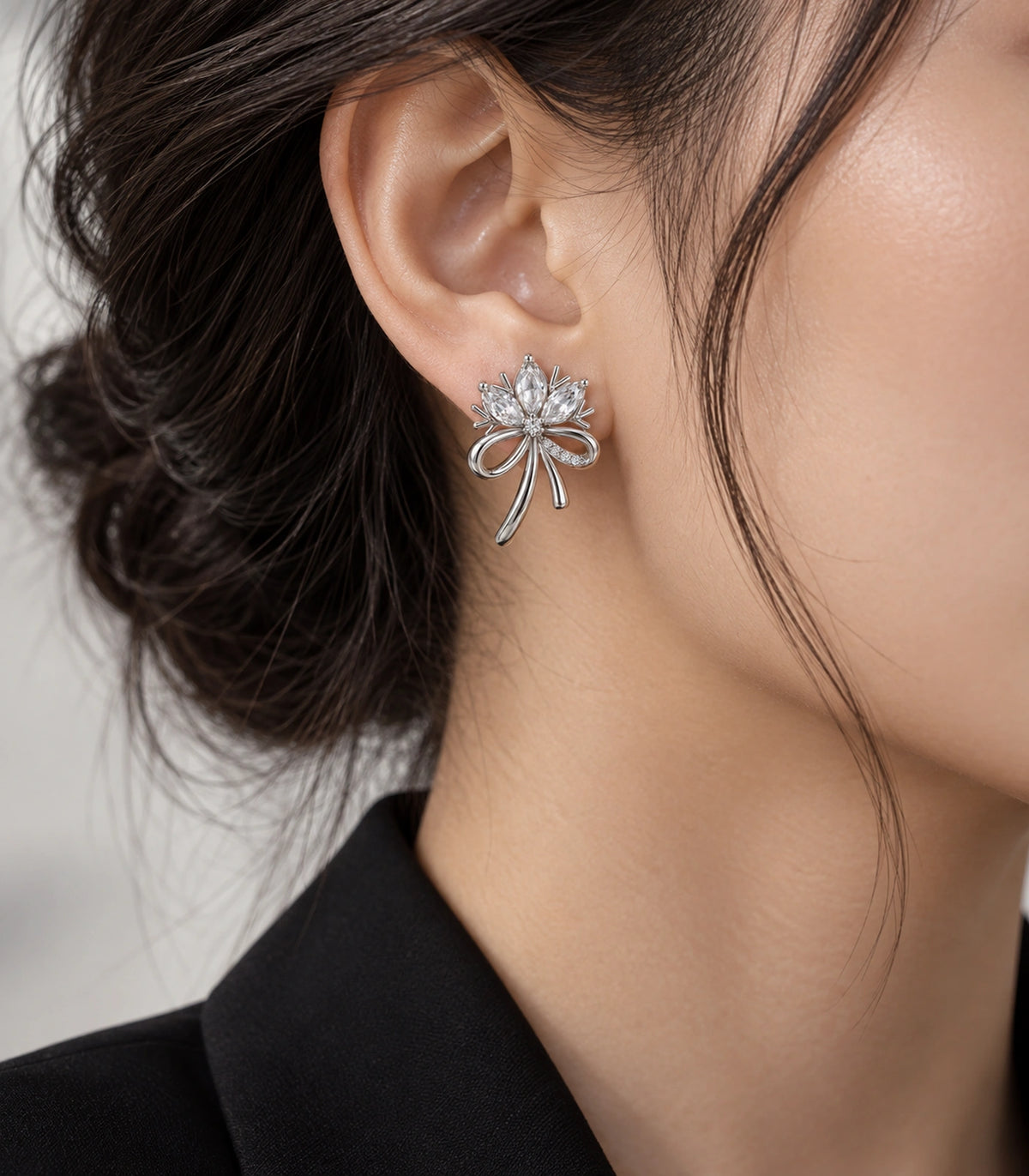 JIMIKI Silver-Tone Three-Petal Crystal Flower Bow Stud Earrings in Silver / Clear, editorial model view