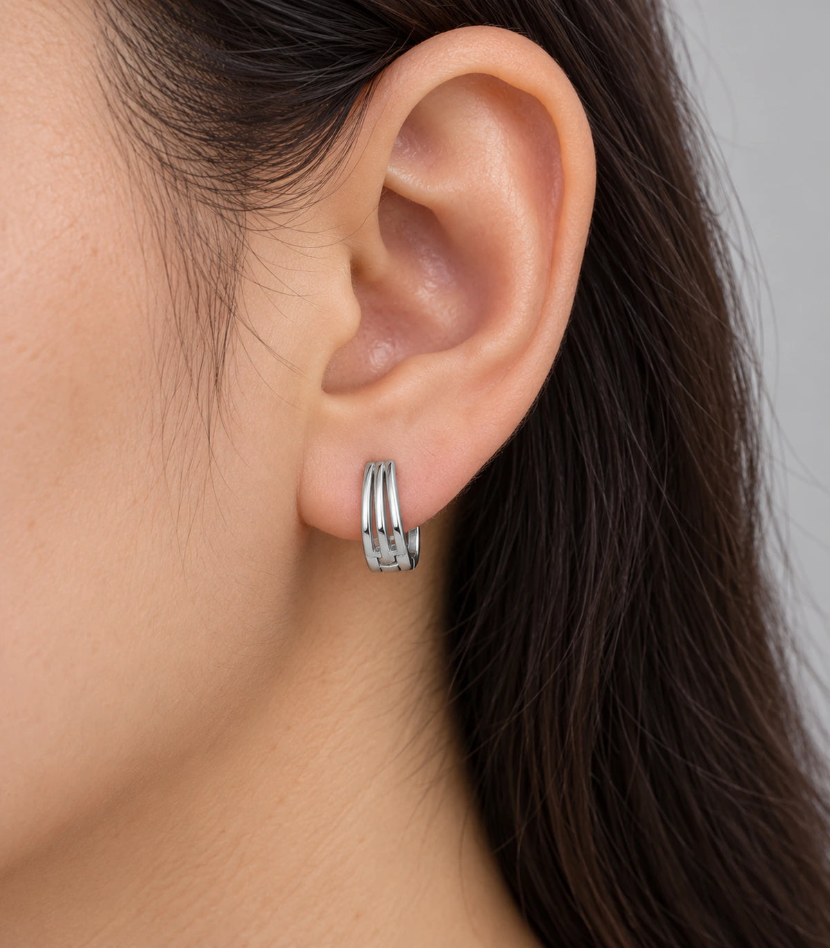 JIMIKI Silver Triple Open Rail Huggie Hoop Earrings, shown worn on the ear #color_silver