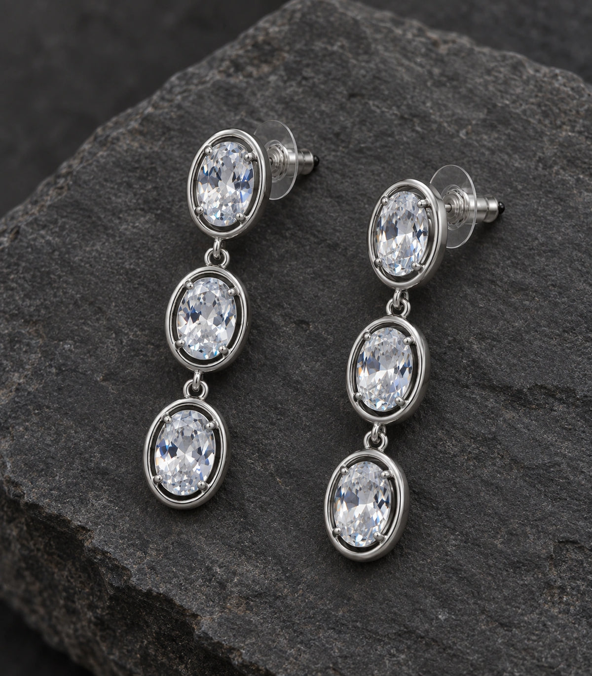 JIMIKI Triple Oval Crystal Drop Earring Pair in Silver tone, editorial flat lay #color_silver tone