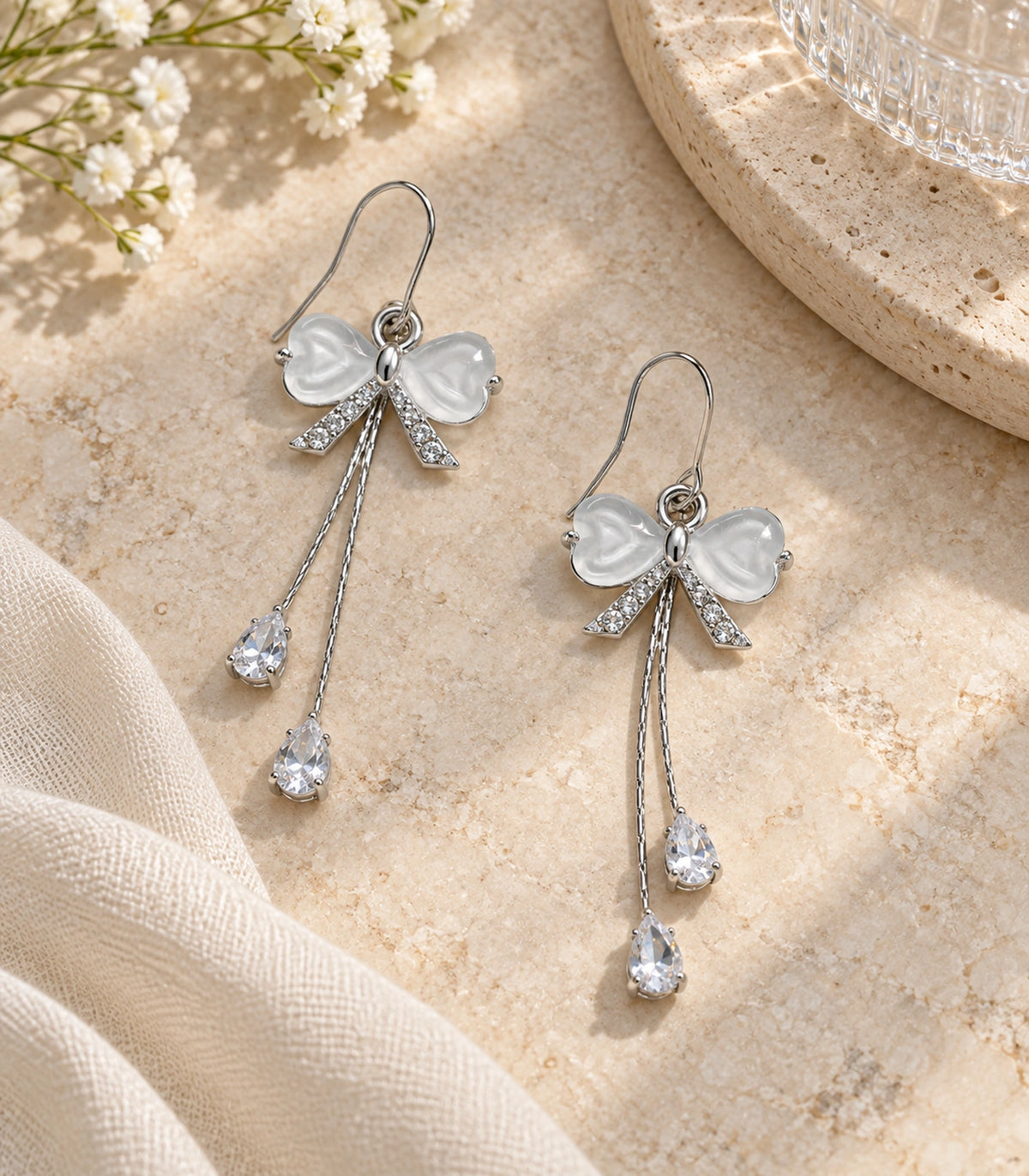 JIMIKI Silver Tone White Bow Twin Pear Chain Earring Pair in Silver-tone, editorial flat lay