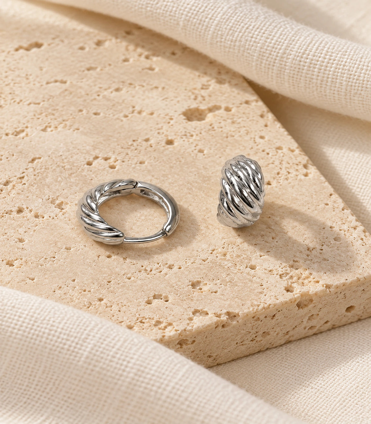 JIMIKI Twisted Rope Huggie Earrings in Silver — editorial flat lay #color_silver