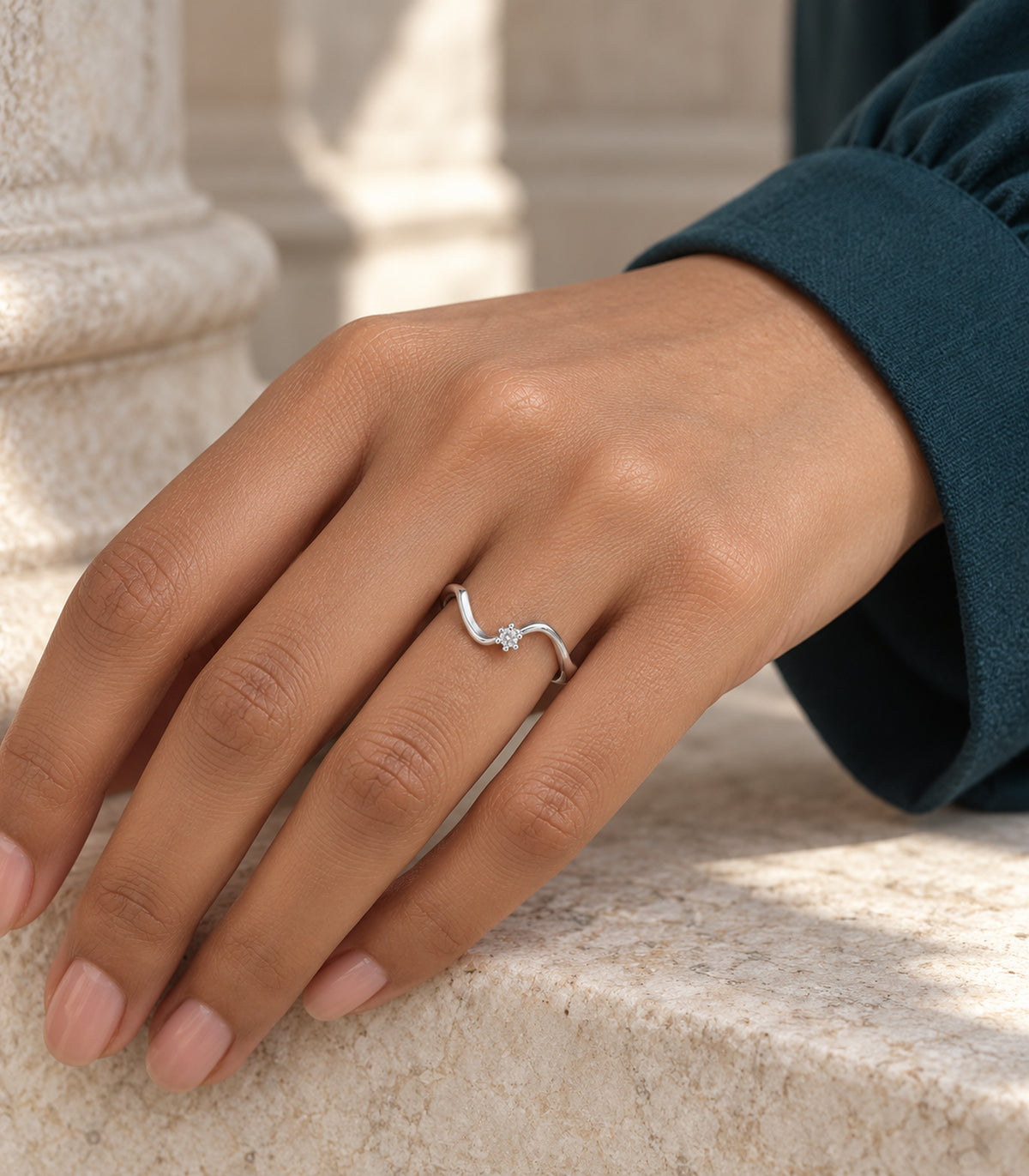 Silver-tone wave ring worn on a hand with a dark teal sleeve