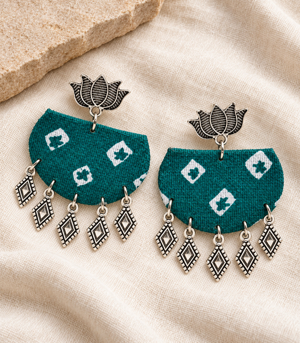 Teal fabric lotus diamond charm earrings - editorial flatlay view