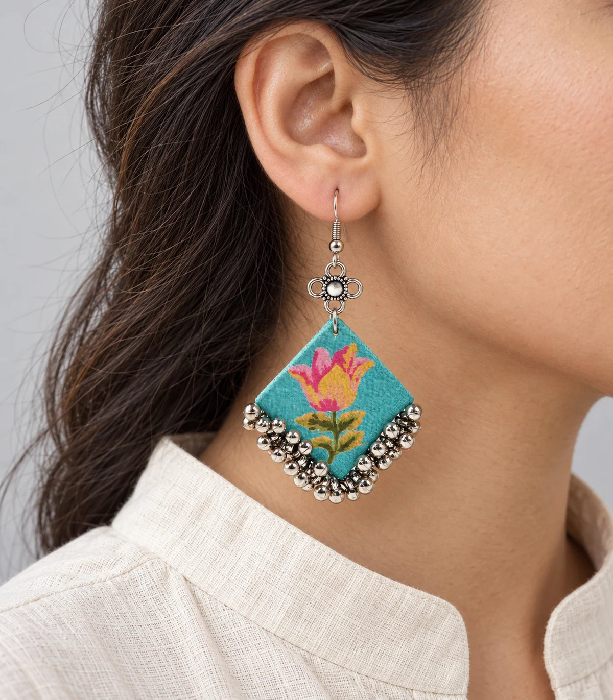 Close view of turquoise tulip fabric earring and silver-tone bell fringe
