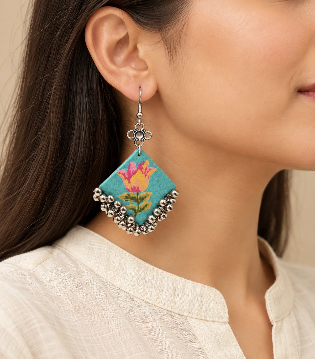 Single turquoise floral fabric ghungroo earring worn at the ear