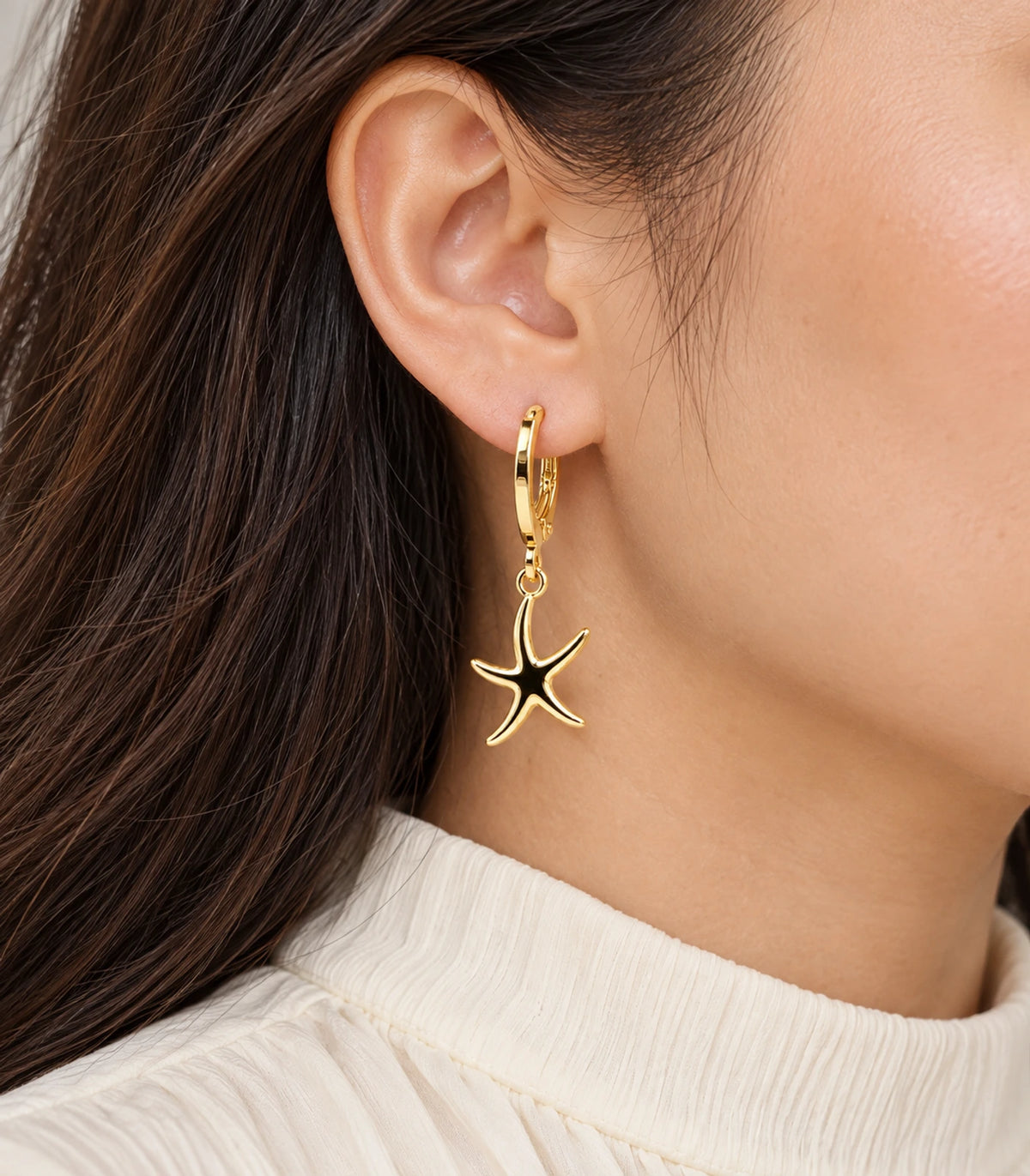 Closeup of the gold-tone five-arm starfish hoop earring from the set