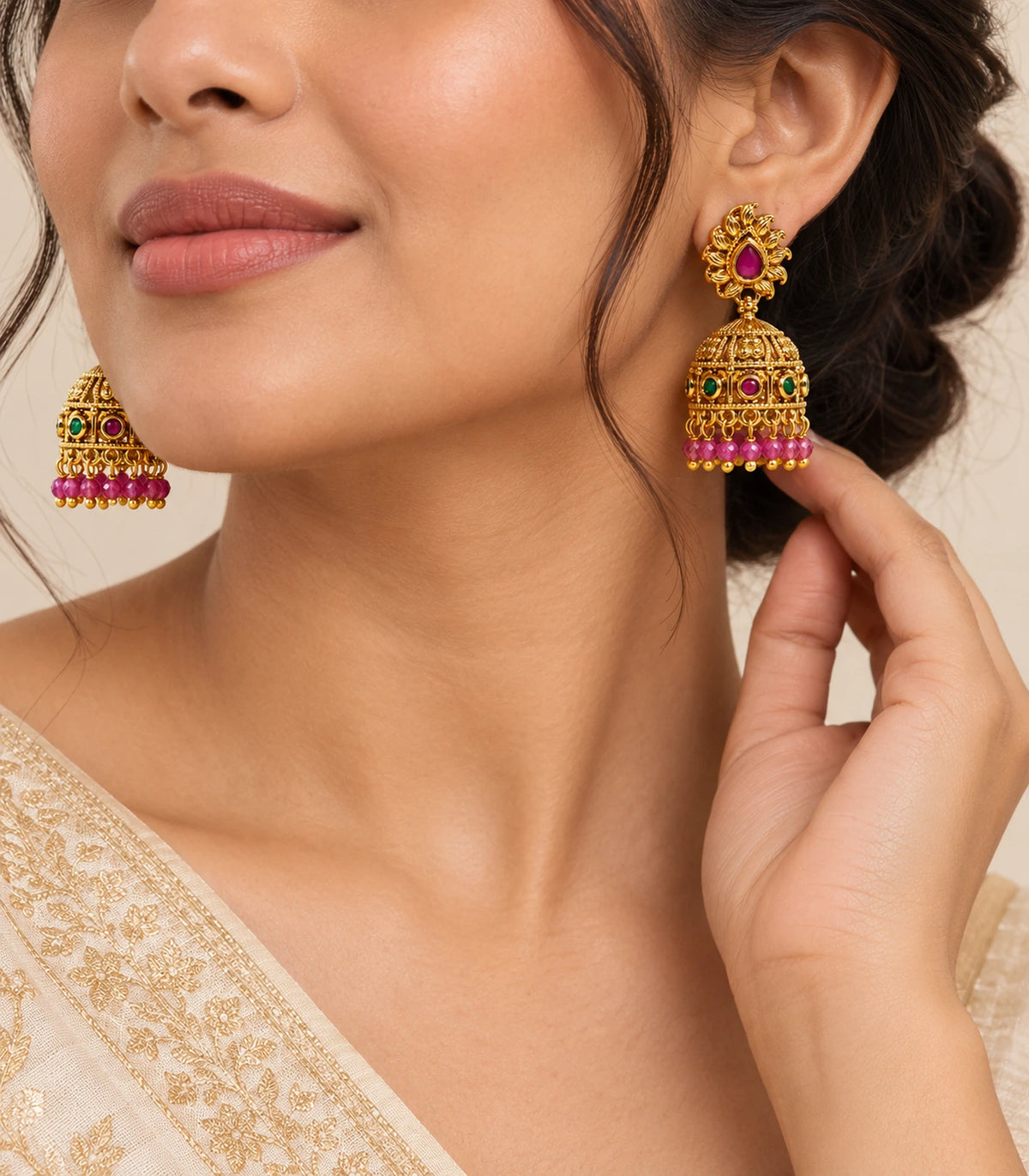 Antique gold-tone magenta and green flame jhumka earrings worn with an ivory outfit