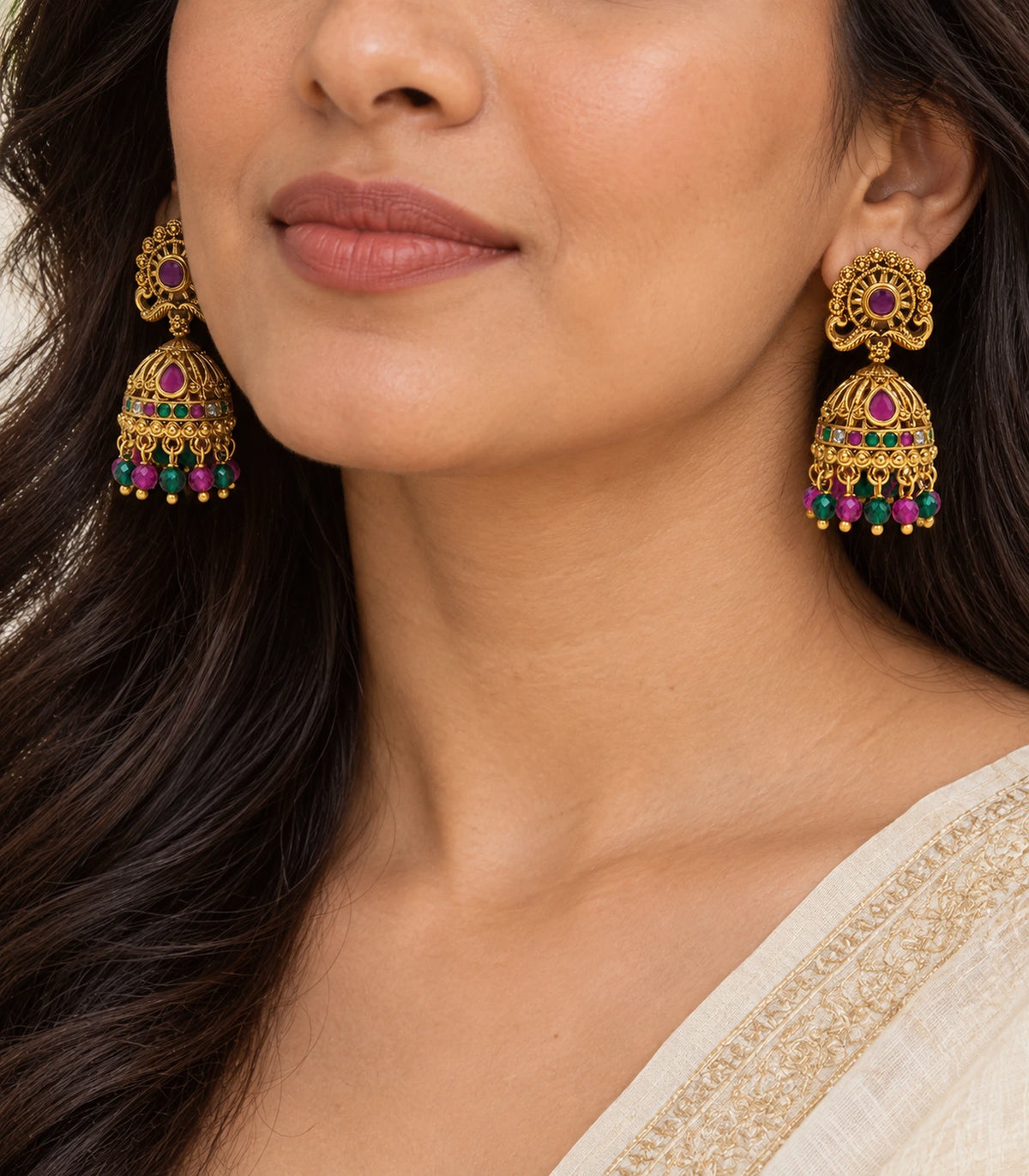 Closeup of magenta and green peacock jhumka earrings worn naturally, showing the dome and beaded fringe