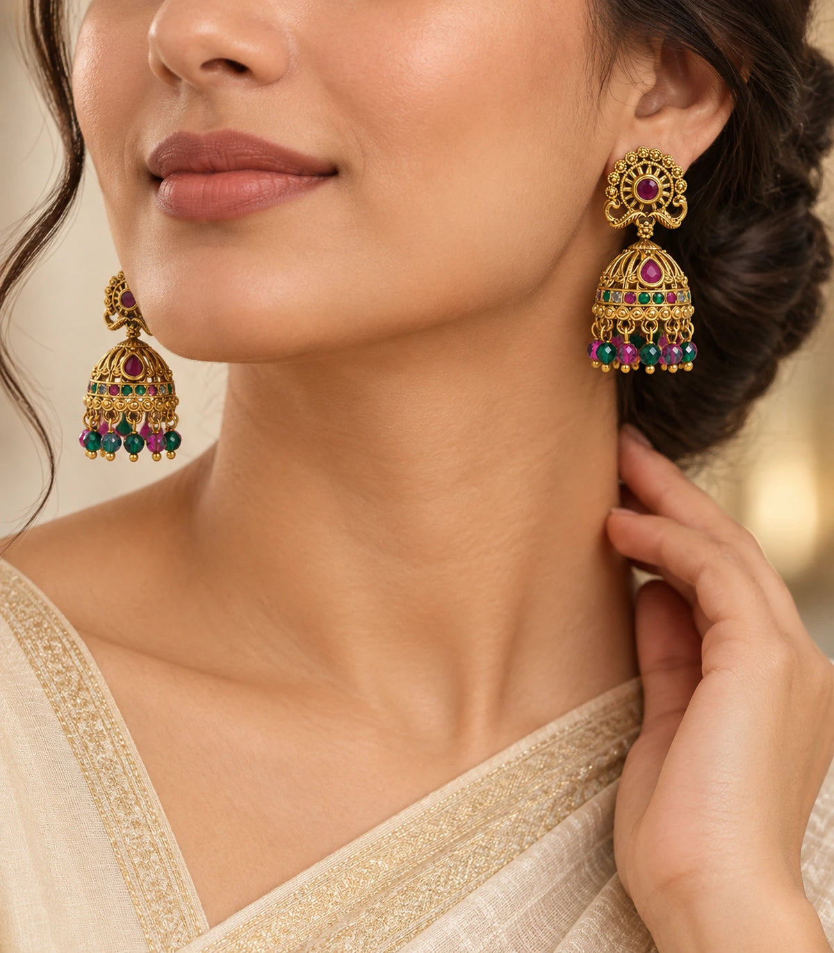 Editorial worn view of antique gold tone magenta and green peacock jhumka earrings