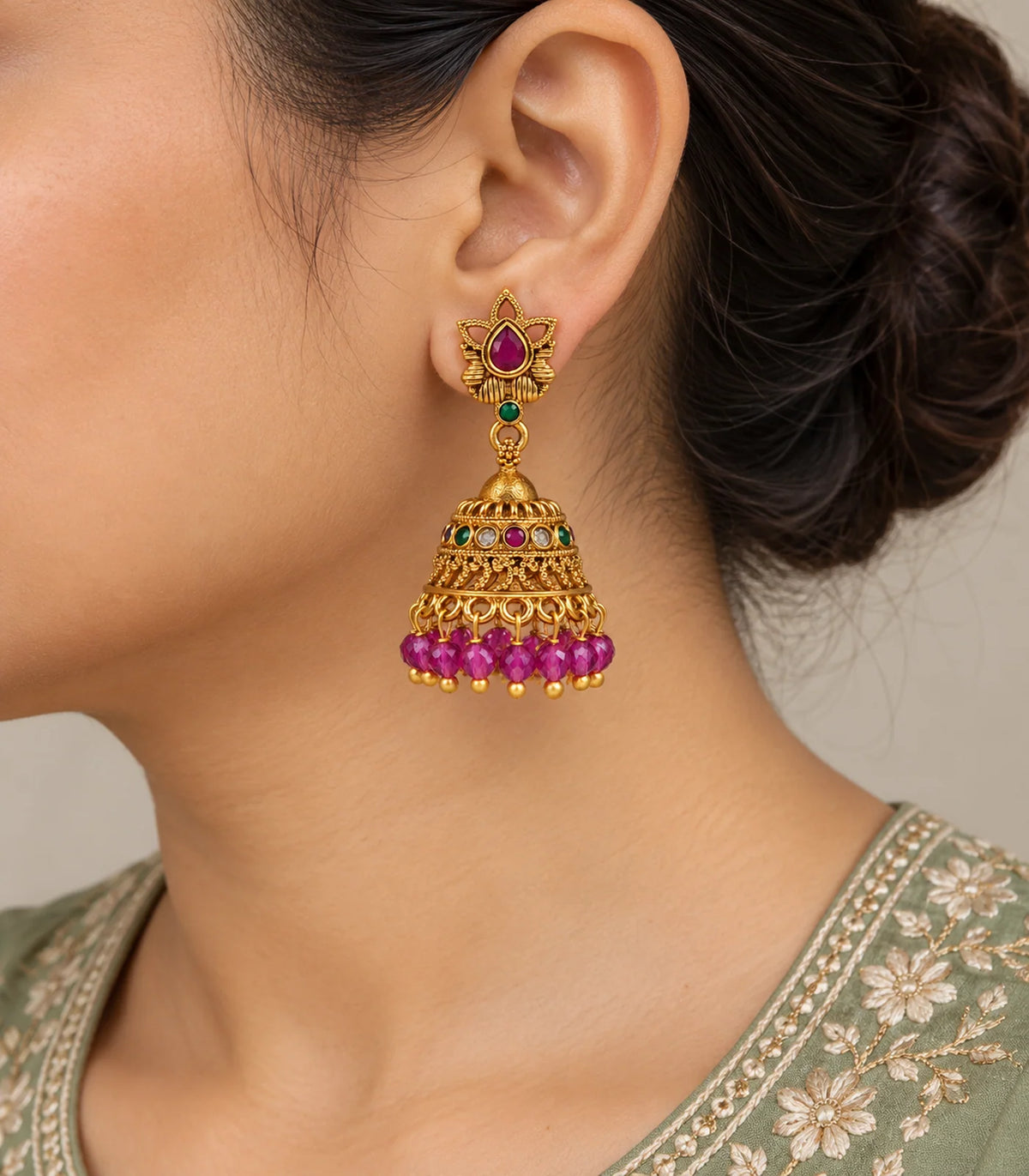 Close view of worn magenta lotus jhumka earring with green connector and faceted bead fringe