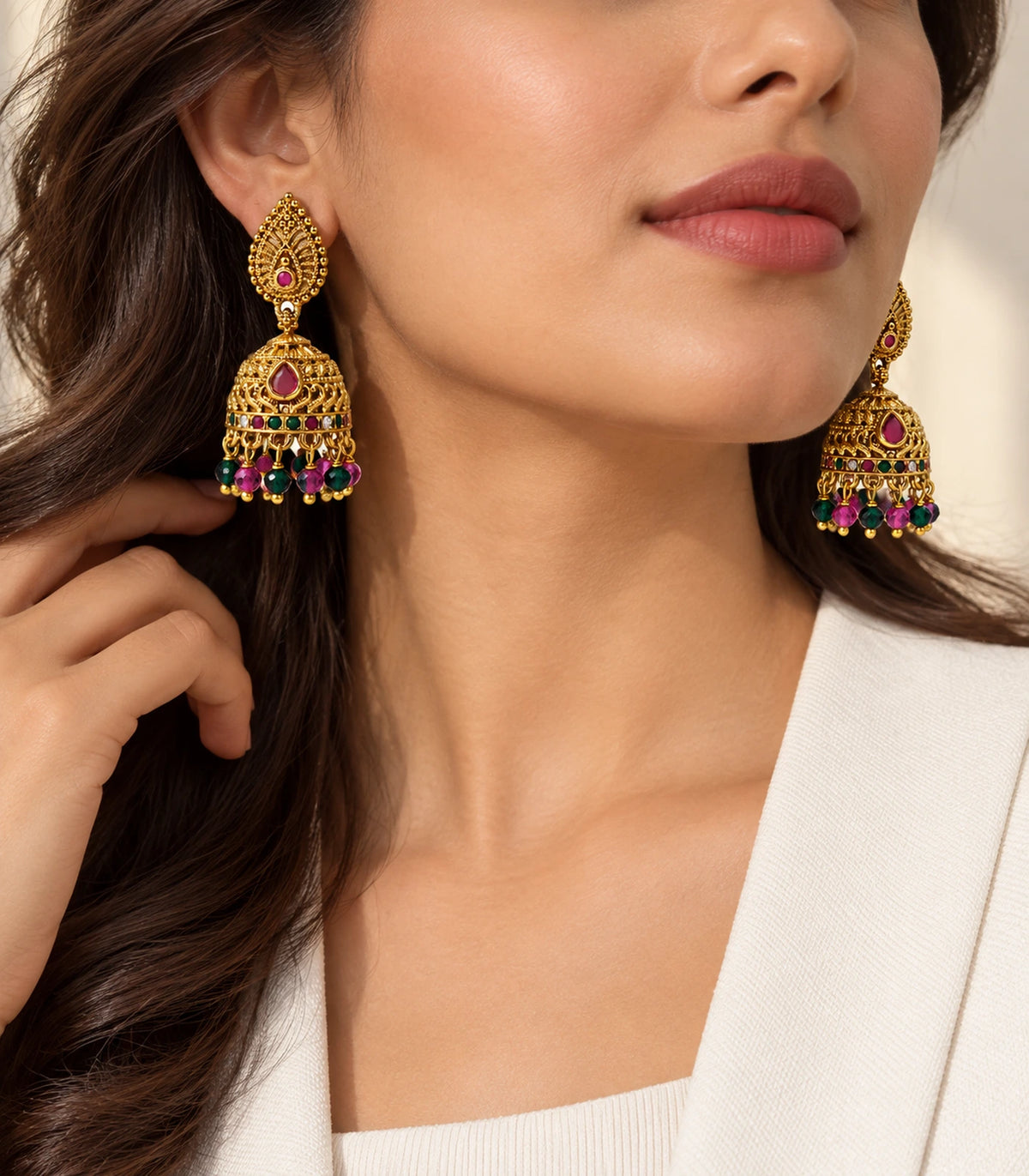 Editorial worn view of antique gold-tone jhumka earrings with magenta accents and green bead fringe