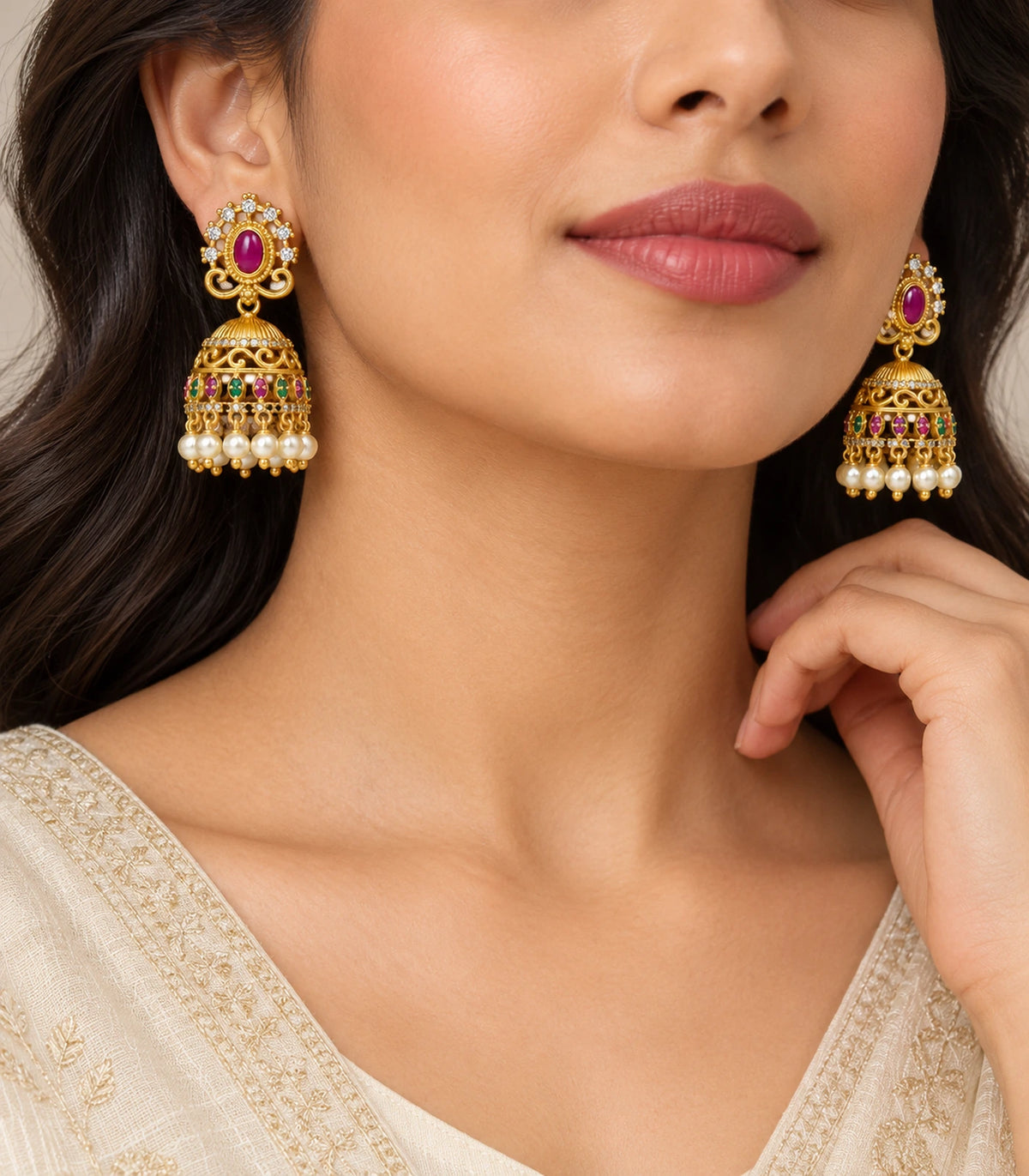 Antique gold-tone magenta and green pearl jhumka earrings worn with an ivory outfit