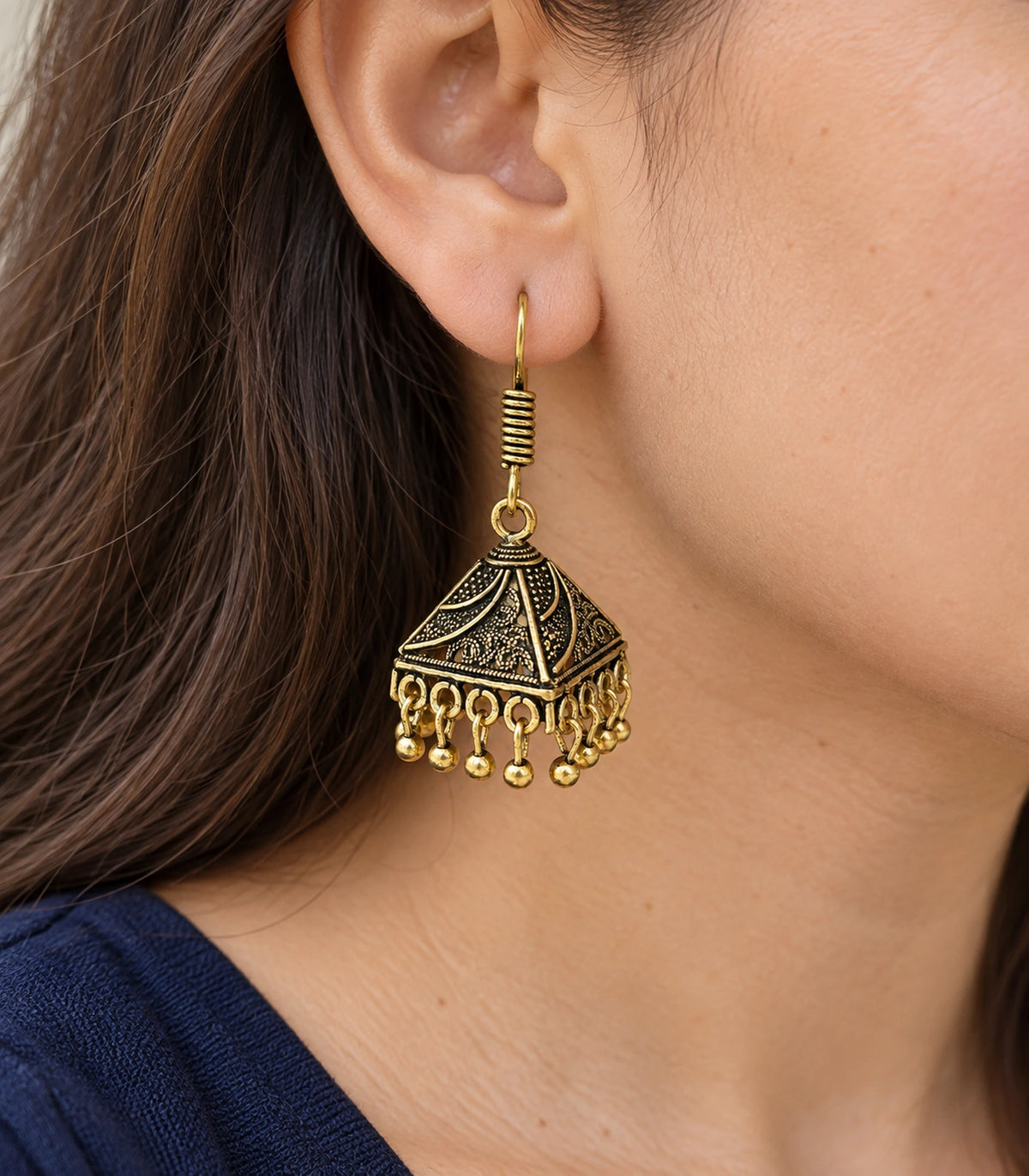 JIMIKI Antique Gold Paisley Pyramid Jhumka Earrings - earring worn with a clear view of the design #color_antique-gold
