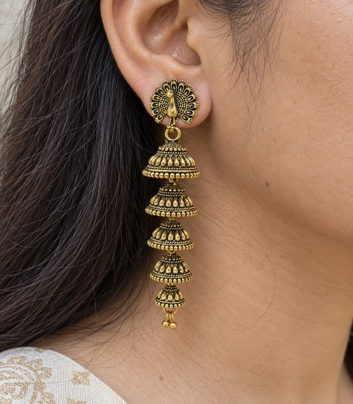 JIMIKI Peacock Five Tier Jhumka Earrings in Antique Gold - close-up details #color_antique-gold