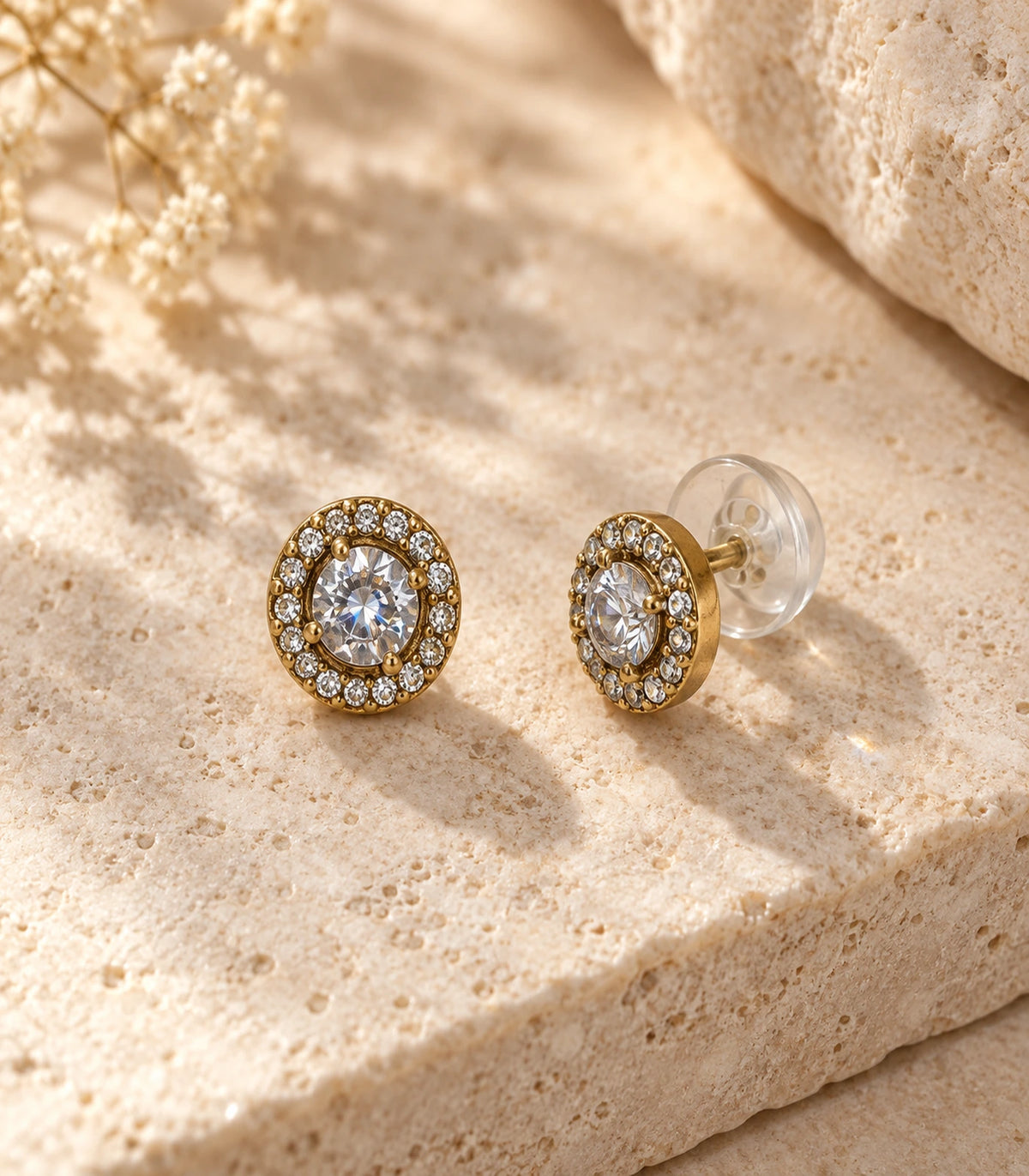 JIMIKI Antique Gold Round Crystal Halo Stud Earrings, matching pair arranged on a pale textured stone surface #color_antique gold