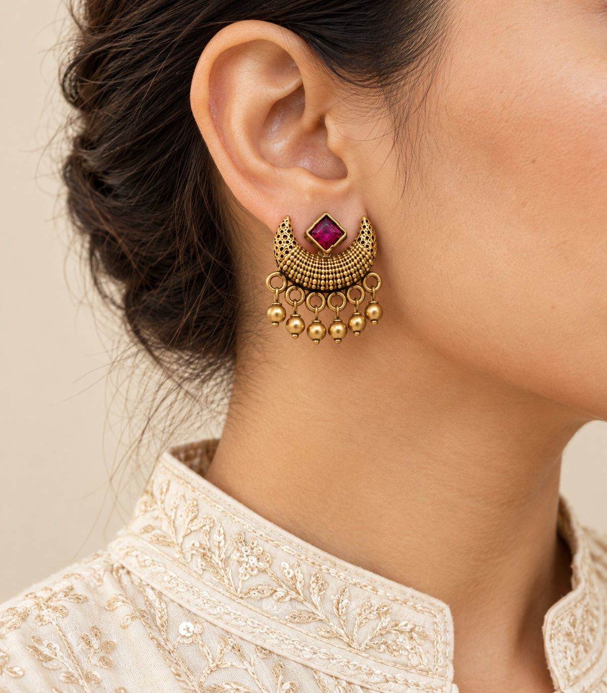 Magenta square crescent earring with gold-tone ball fringe worn closeup