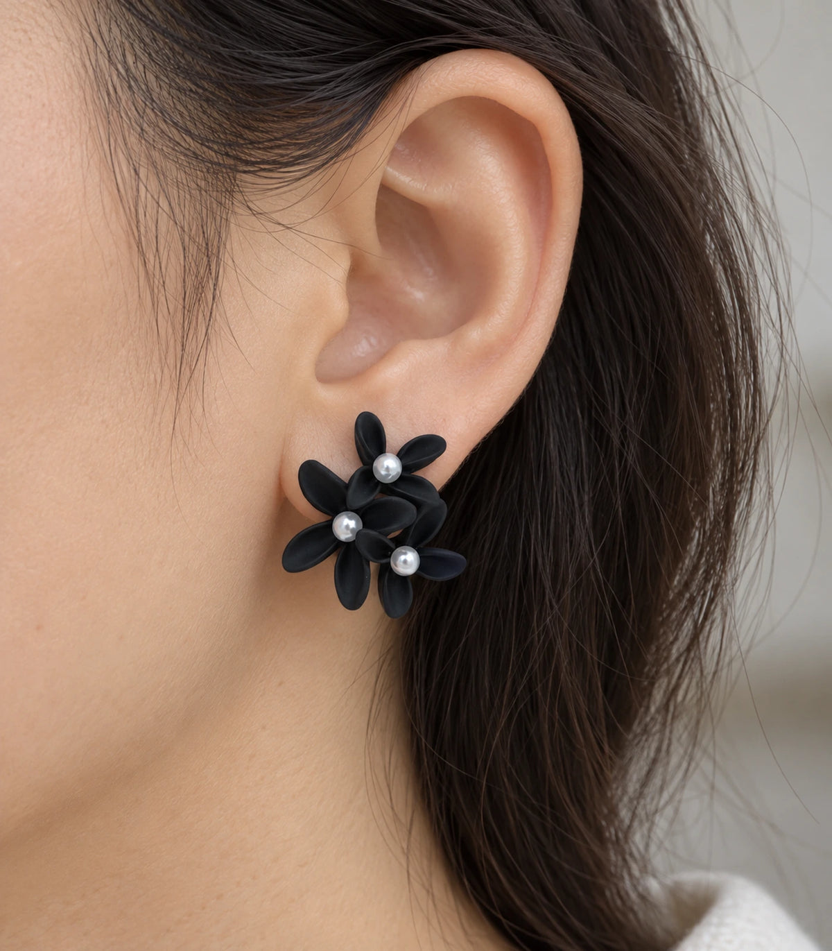 JIMIKI Black cascading floral cluster stud earrings, close-up of the three pearl-like centres and curved petals #color_black