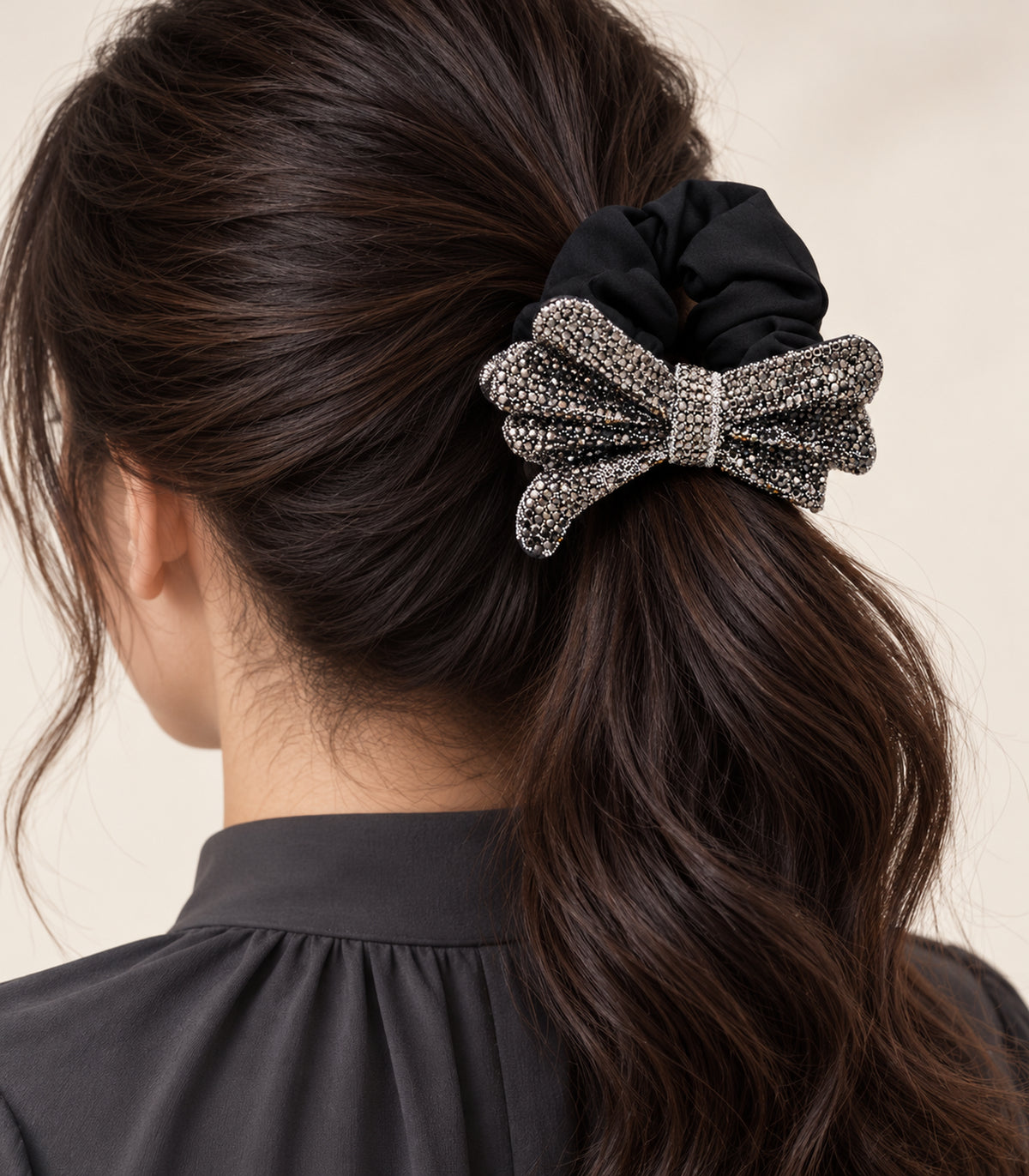 Black crystal-like bow scrunchie worn in a ponytail