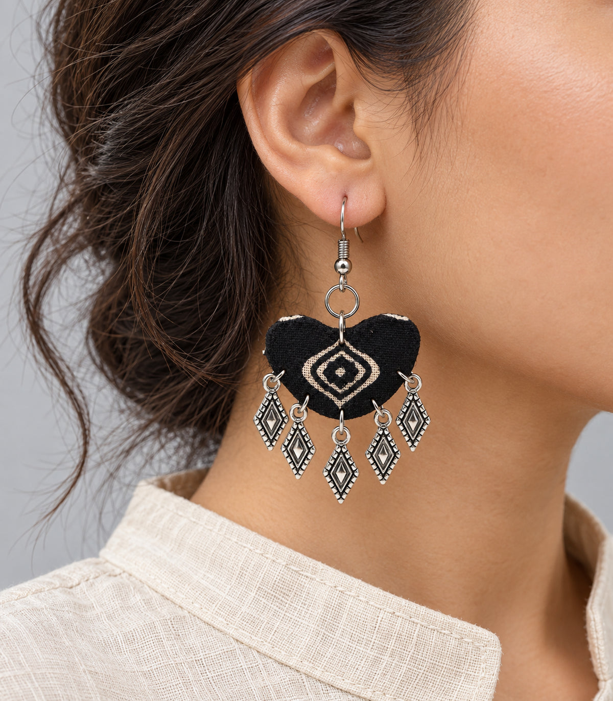 Worn detail of the fabric print, circular connector and dangling diamond-shaped charms
