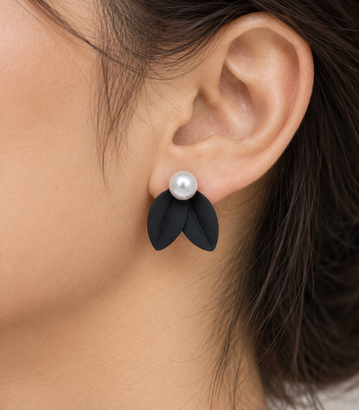 JIMIKI Double Leaf Pearl Stud Earrings in Black — close-up of the earring worn on the ear #color_black
