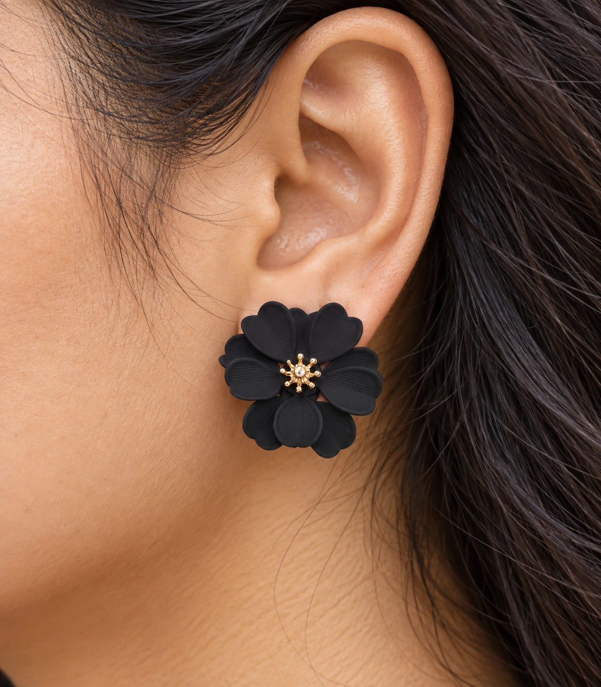 JIMIKI Black Layered Daisy Stud Earrings - layered scalloped petals and gold-tone centre worn close-up #color_black