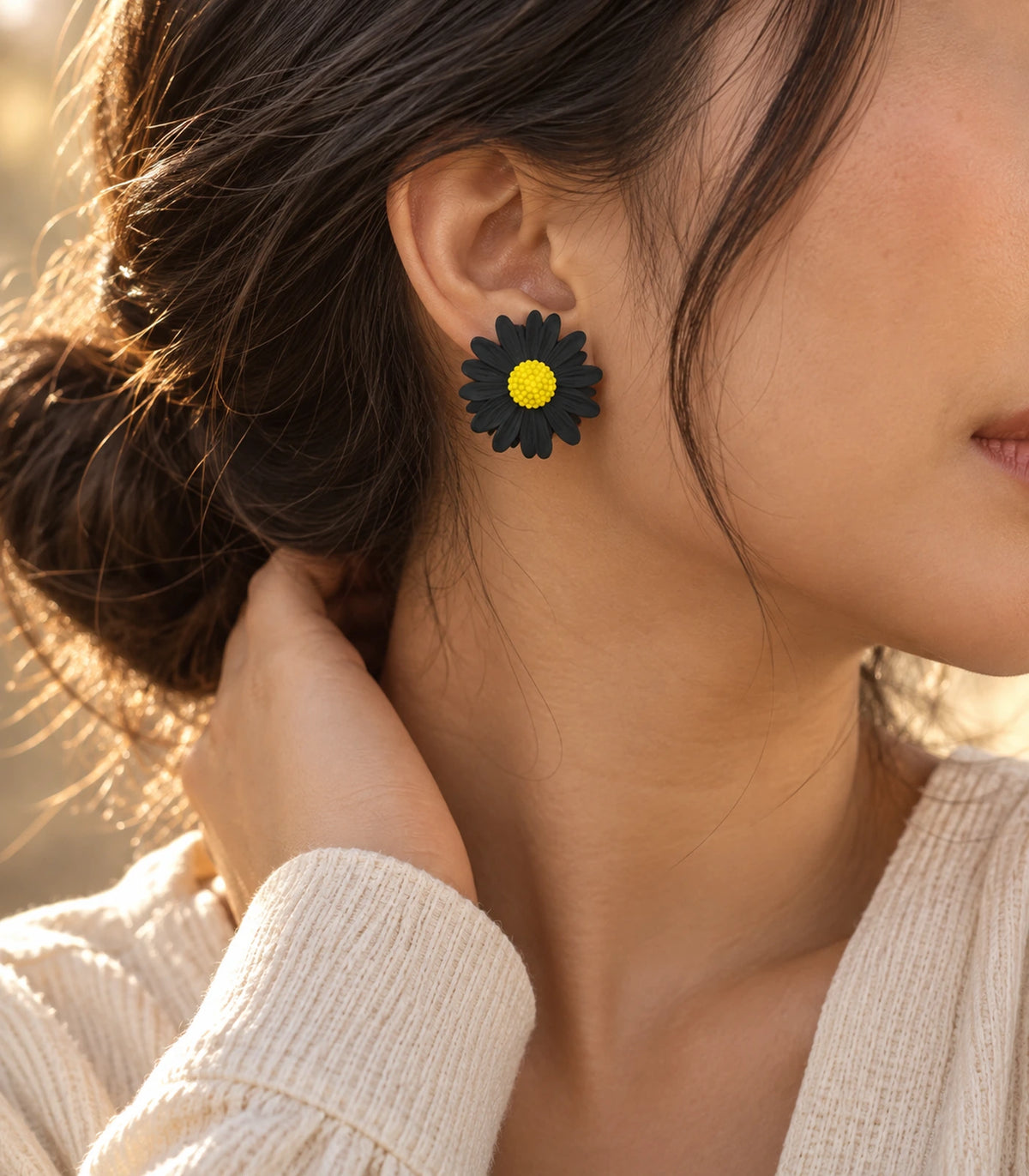 JIMIKI Black yellow centre daisy stud earrings, earring worn in a warm editorial setting #color_black