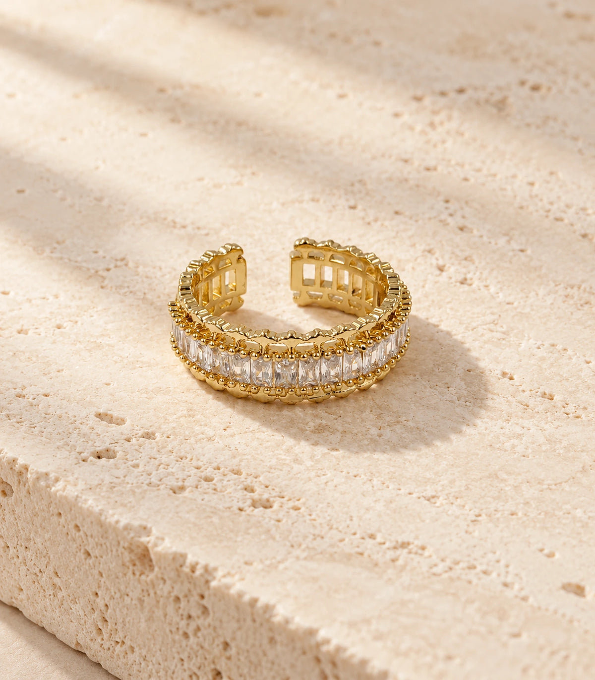 Complete gold-tone open ring styled on a textured stone surface