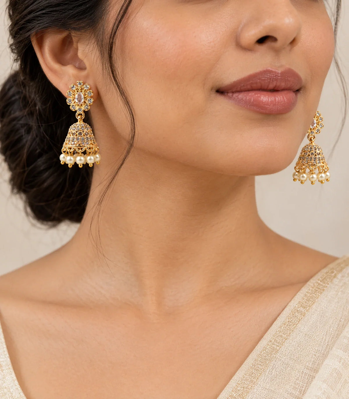 Gold-tone champagne floral jhumka earrings with cream pearl-like bead fringes worn with an ivory outfit