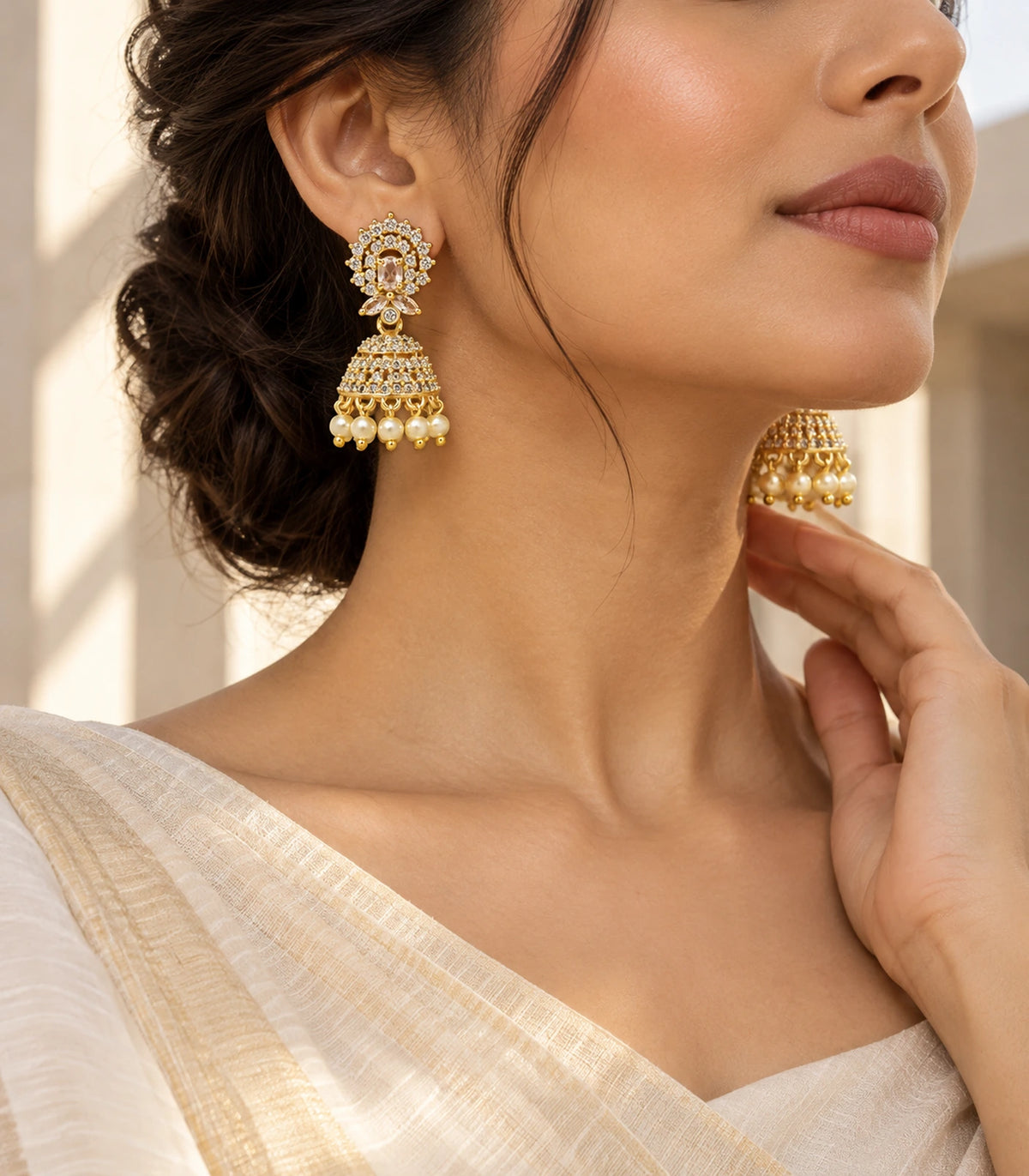 Turned worn view of gold-tone champagne halo jhumkas and pearl-style fringe with ivory styling