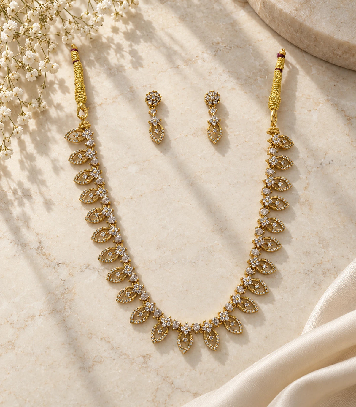 Complete gold-tone necklace and two matching clear drop earrings arranged on a neutral surface