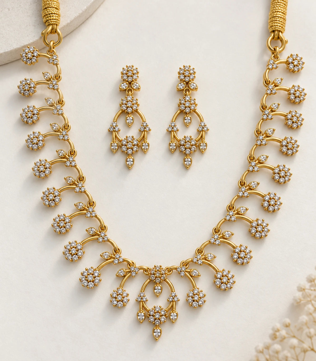 Detailed view of gold-tone clear floral necklace and matching open-loop earrings