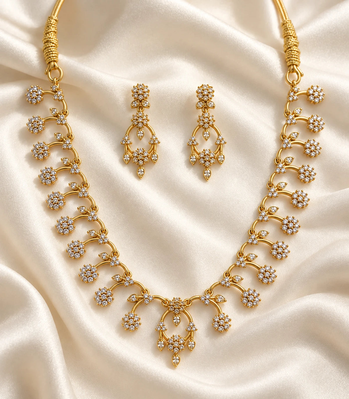 Gold-tone clear floral necklace and matching earrings arranged on ivory fabric