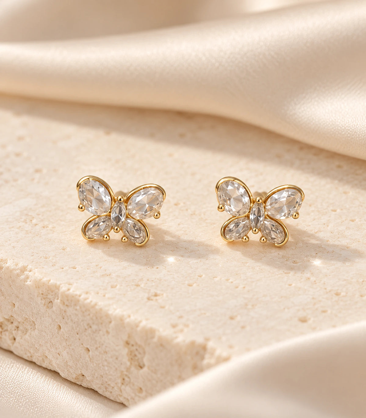JIMIKI Gold Crystal Butterfly Stud Earrings — editorial flat lay #color_gold-tone