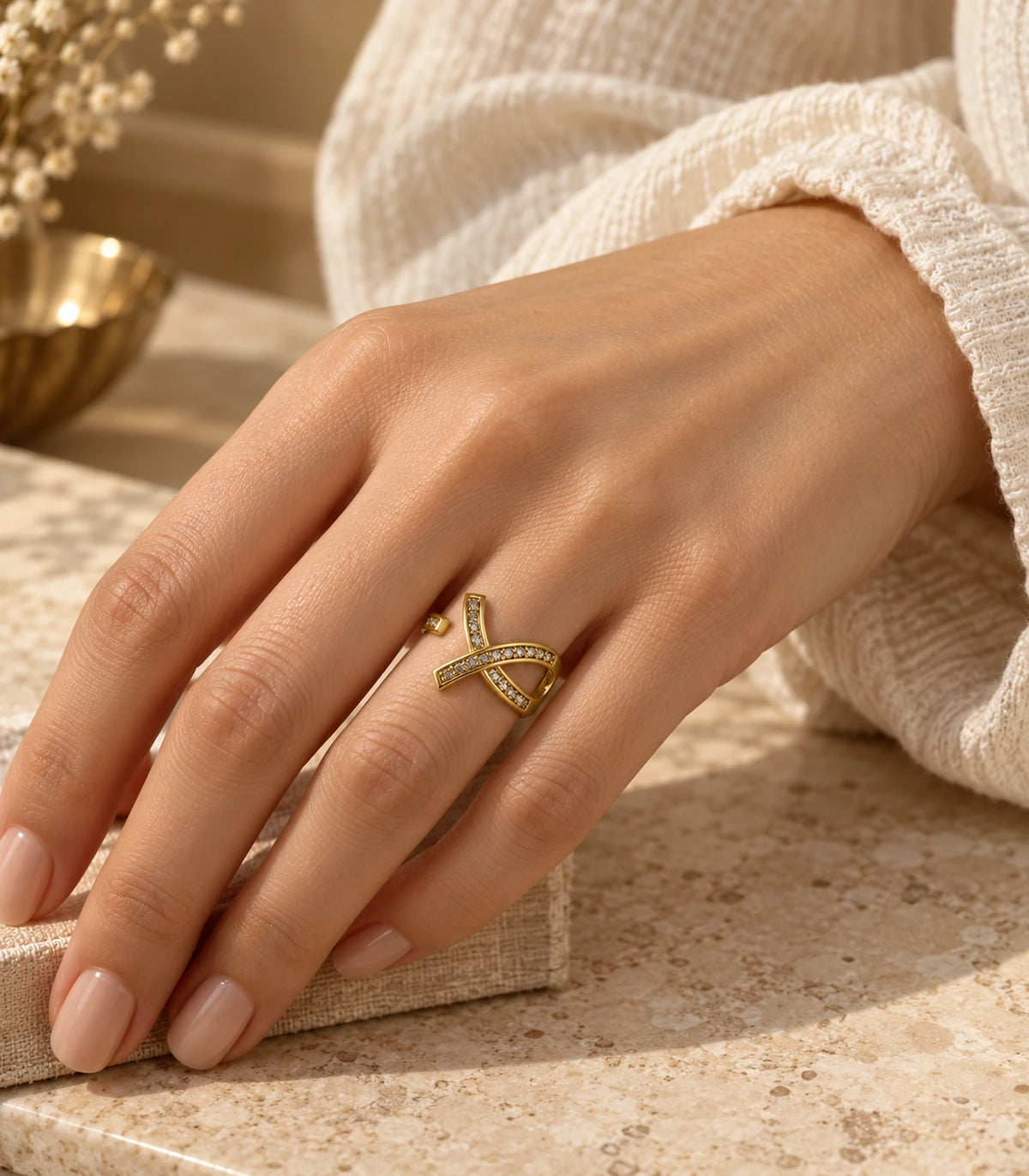 Gold Crystal Crossing Ribbon Open Ring worn beside a knitted sleeve