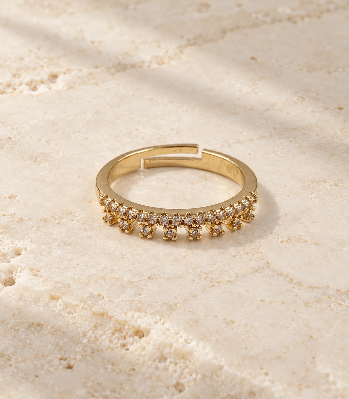 Gold Crystal Fringe Band Ring on a textured stone surface